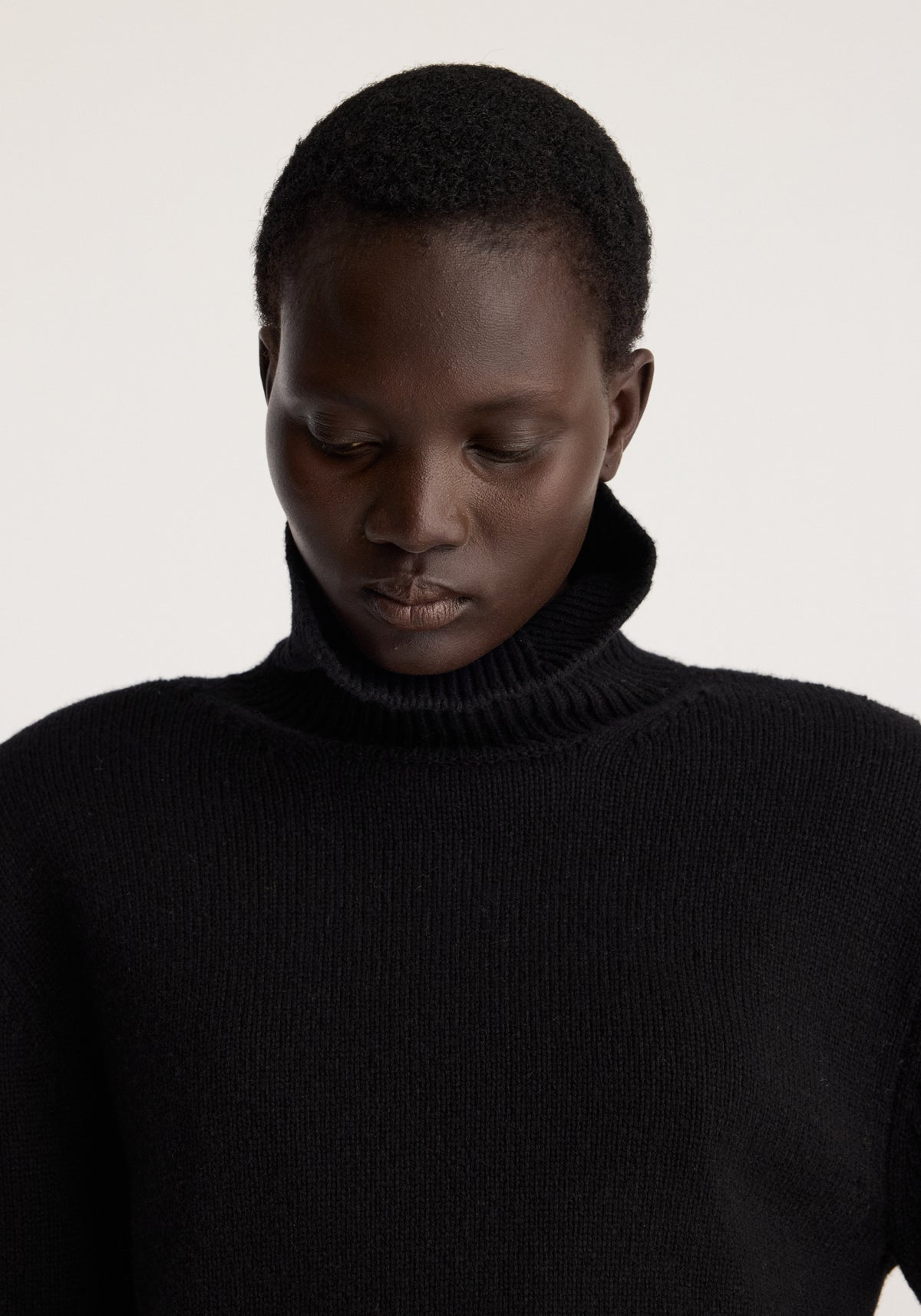 Model wearing the Statement shoulder turtleneck | black with a high ribbed neck and relaxed silhouette against a neutral background