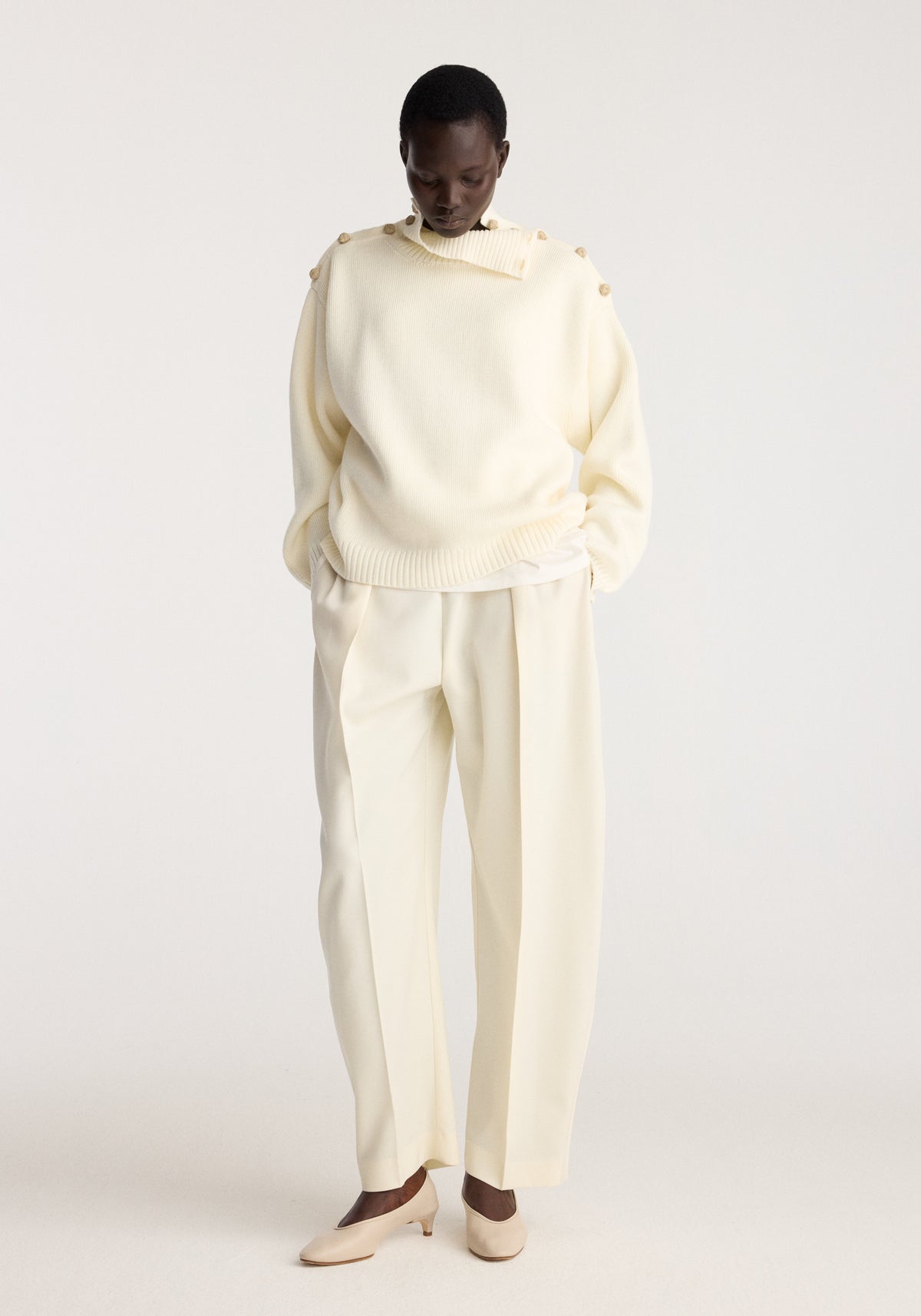 Uneven sailor polo | cream worn by a model with a relaxed fit, sailor collar, long sleeves, and matching cream trousers in a neutral studio setting