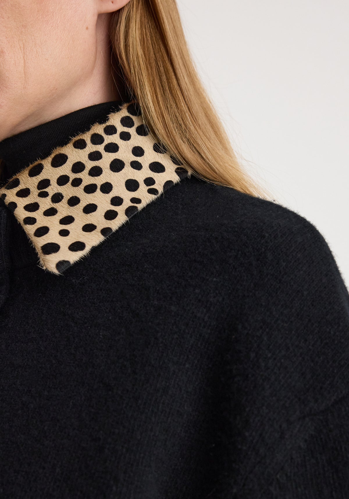 Close-up of a black knitted garment featuring a cheetah print collar detail, showcasing texture and pattern of the Cheetah collar cardigan | black.
