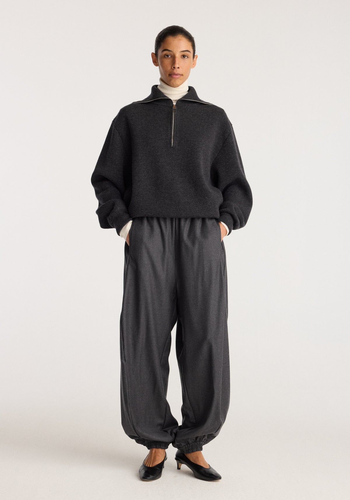 Reversible zipped turtleneck | charcoal worn by a model, featuring a high collar, quarter zip fastening, relaxed fit, and long sleeves in a studio setting