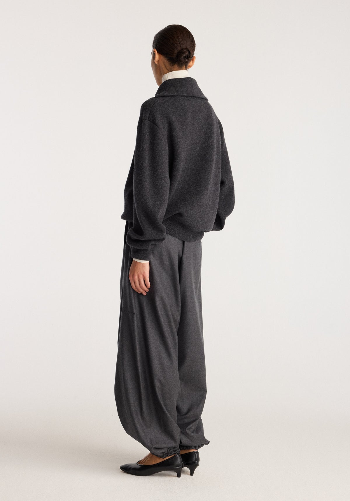 Reversible zipped turtleneck | charcoal shown from the back on a model, featuring a high collar, relaxed fit, and soft charcoal fabric paired with wide trousers