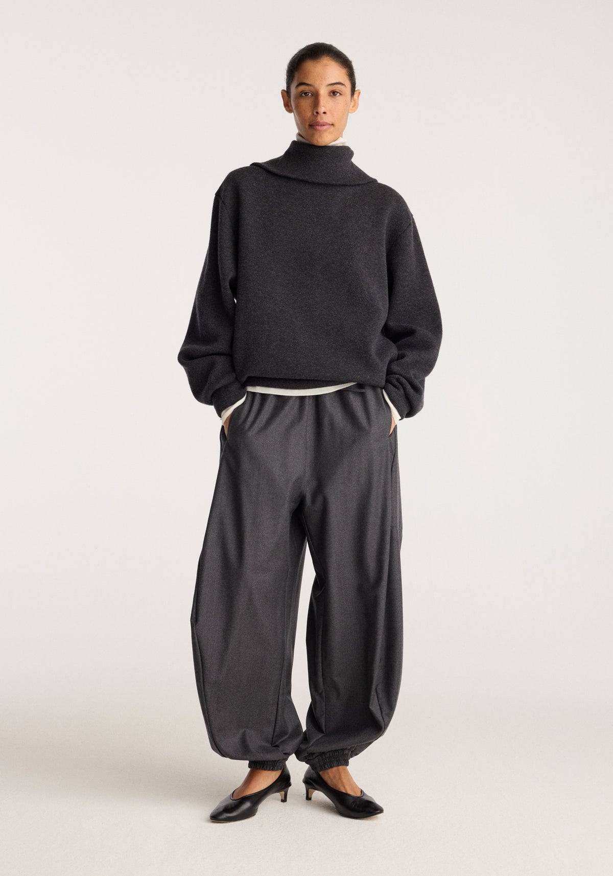 Reversible zipped turtleneck | charcoal worn by a model with loose dark trousers and black flats against a neutral studio background