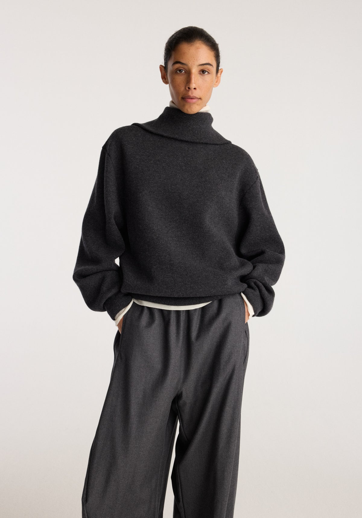 Reversible zipped turtleneck | charcoal shown on a model with a high neckline relaxed fit and long sleeves paired with dark wide leg trousers