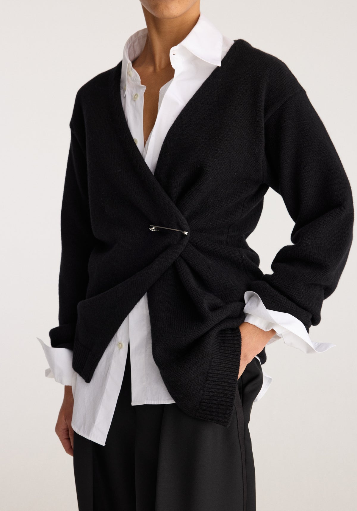 Off-shoulder wrap cardigan | black styled over a white collared shirt with a wrap front, long sleeves, button closure, and ribbed hem