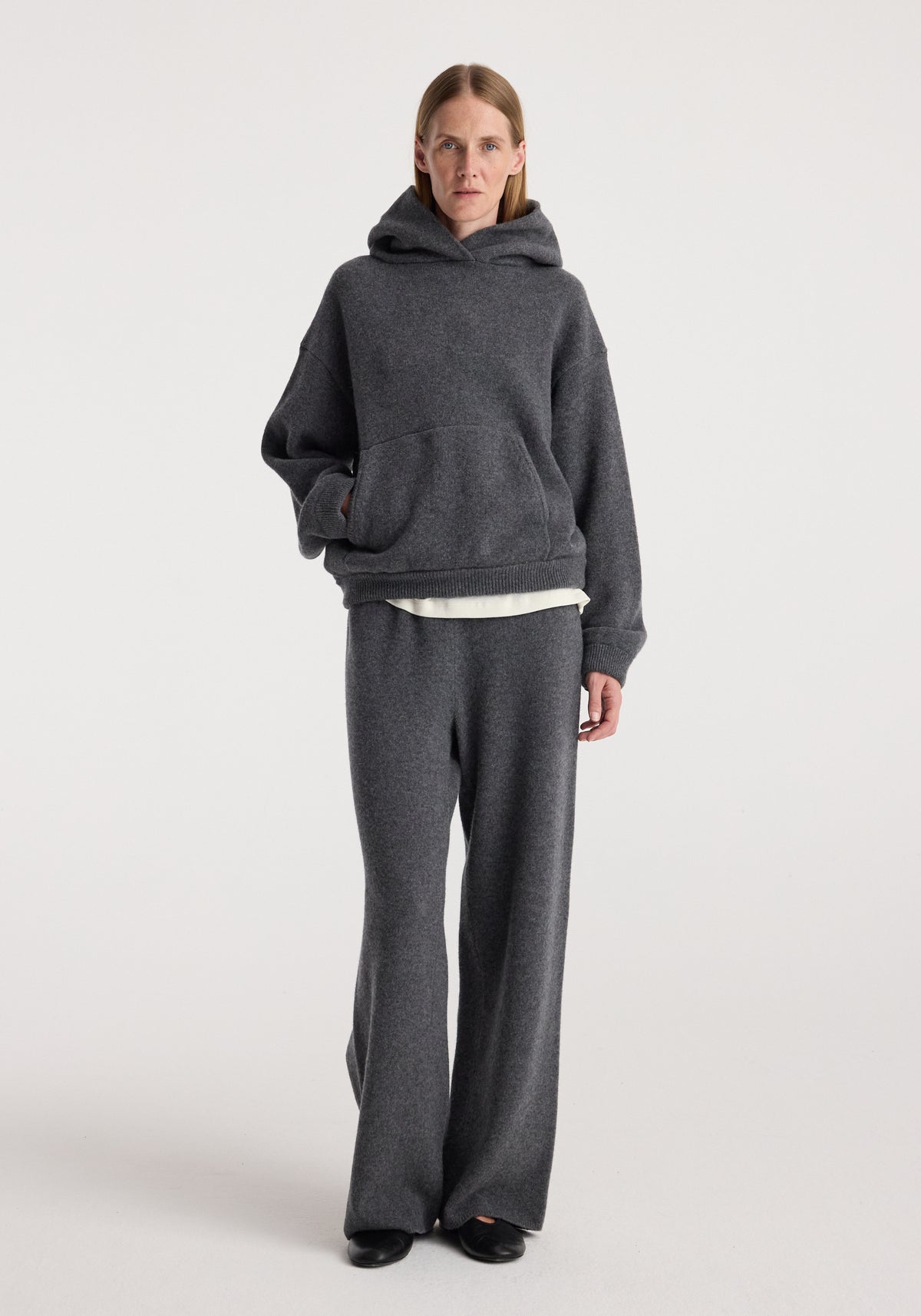 Model wearing the Hooded kangeroo jumper | dark grey melange with matching wide leg trousers in a studio setting