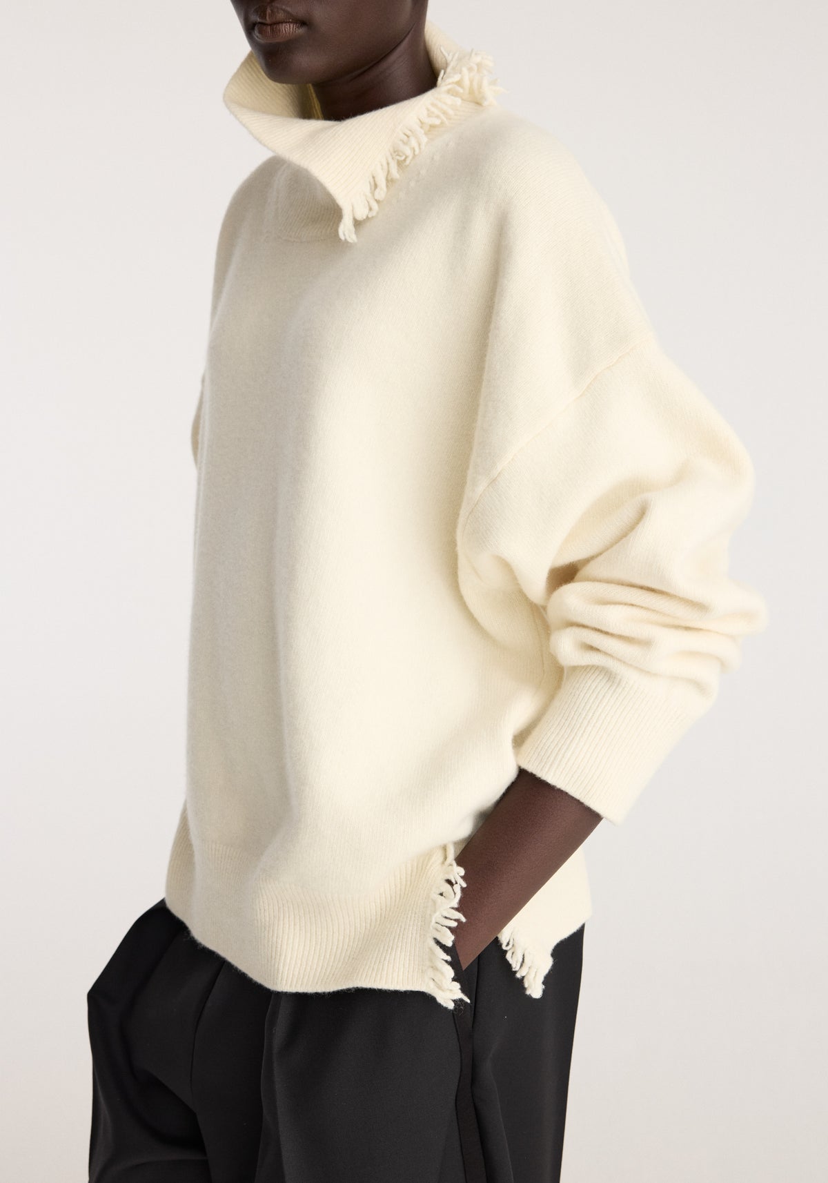 Turtleneck with raw details | off white shown on a model with a fringed collar and hem styled with black trousers