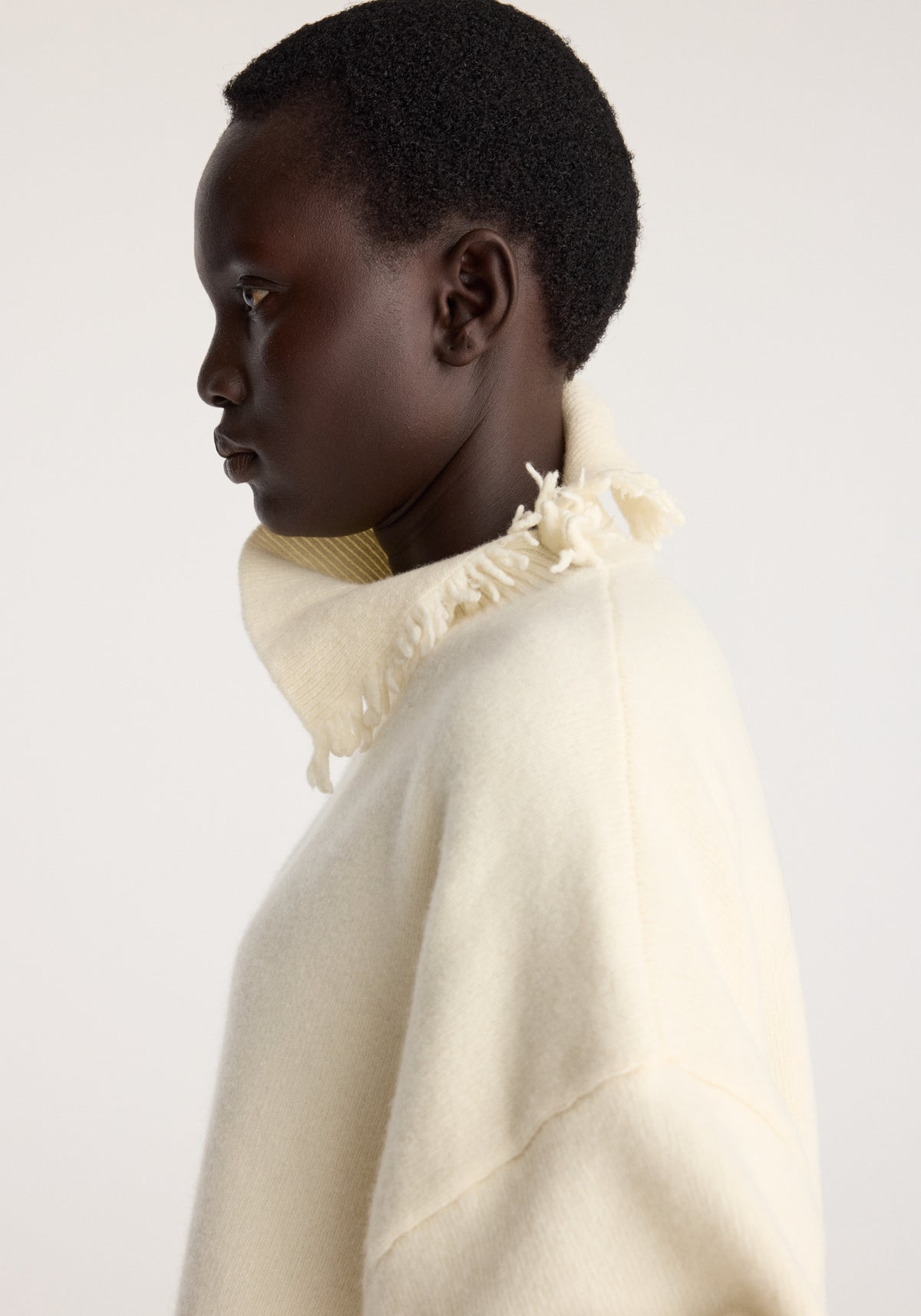 Turtleneck with raw details | off white shown on a model in side profile with a soft cream finish and frayed raw edge around the neck