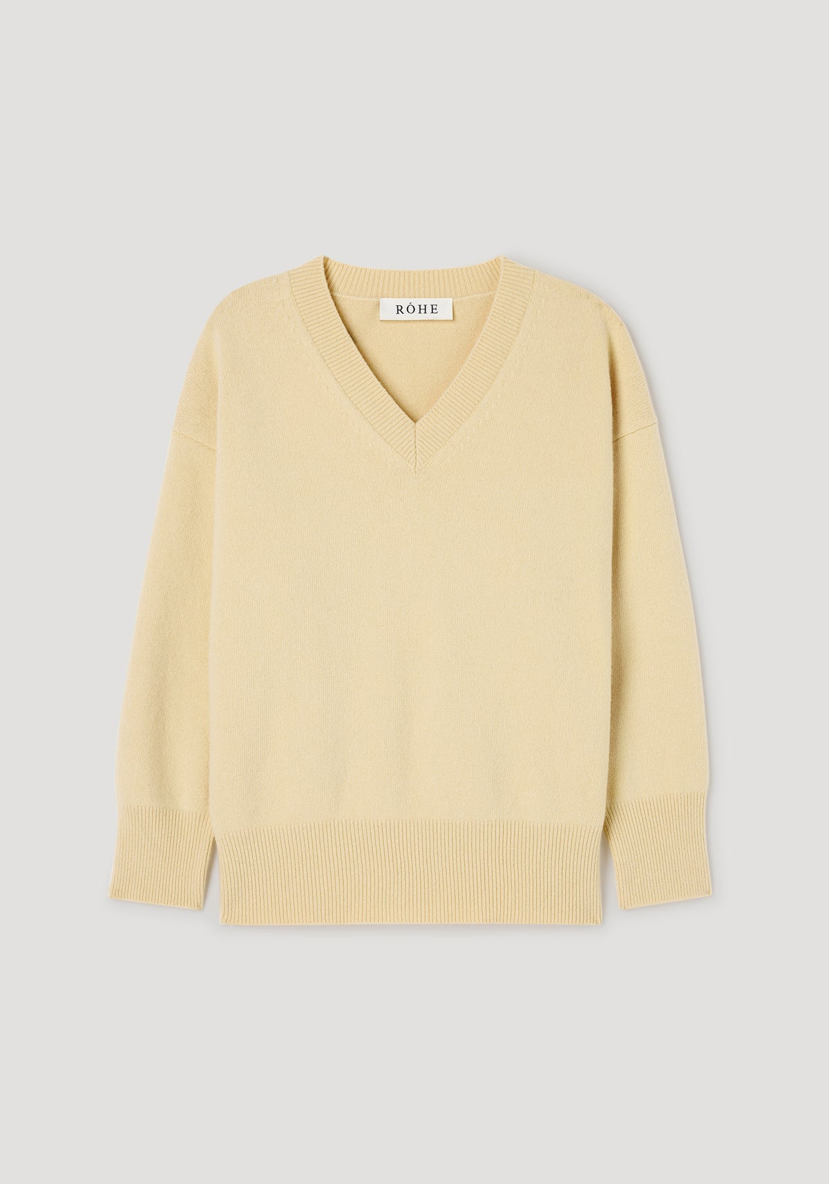 Classic v-neck jumper | butter in a soft yellow shade, featuring long sleeves, ribbed cuffs, and hem, displayed flat on a light background.