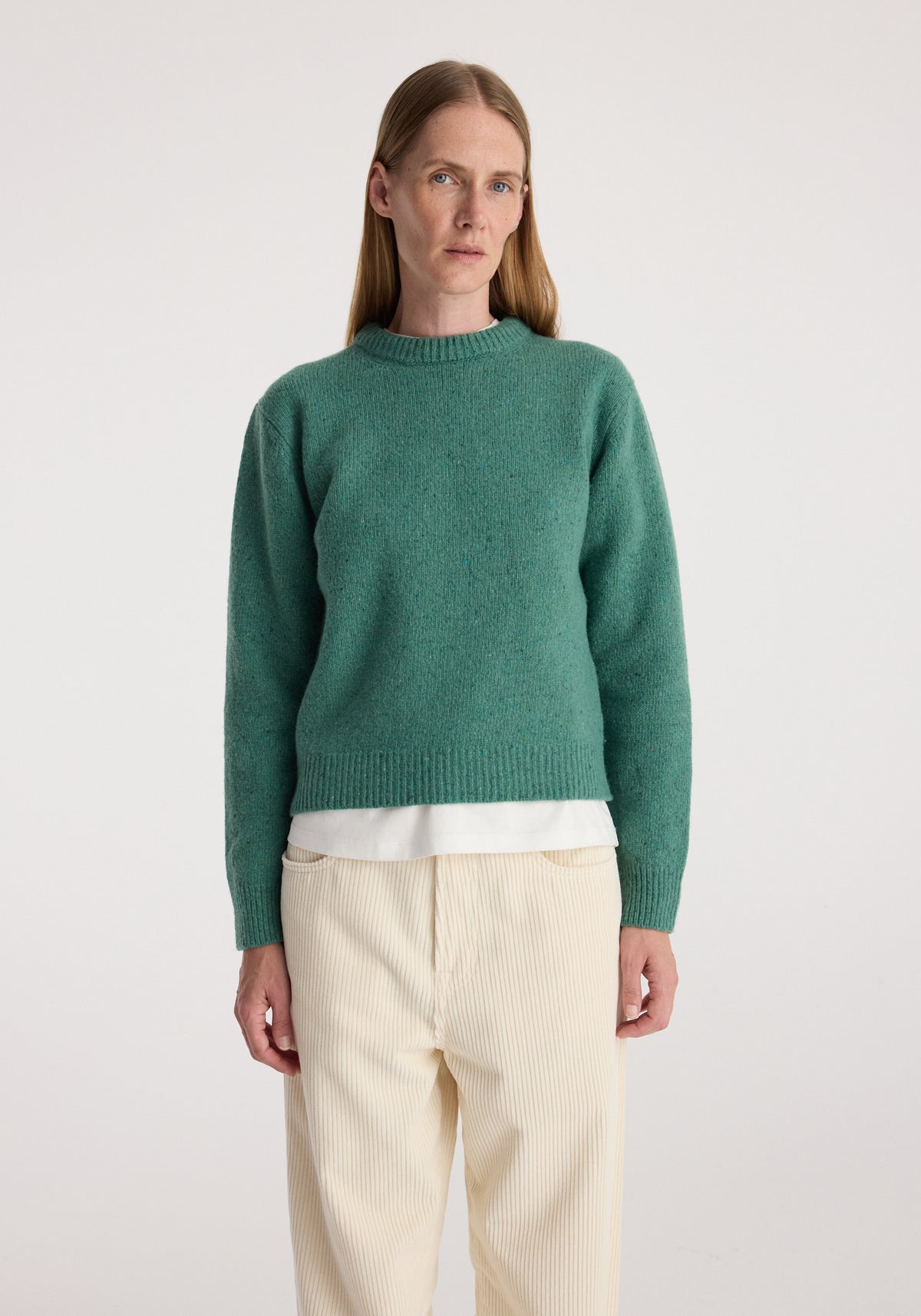 Fitted mouliné crewneck | jade mouliné, a green textured sweater worn with a white shirt and cream trousers by a model against a neutral background