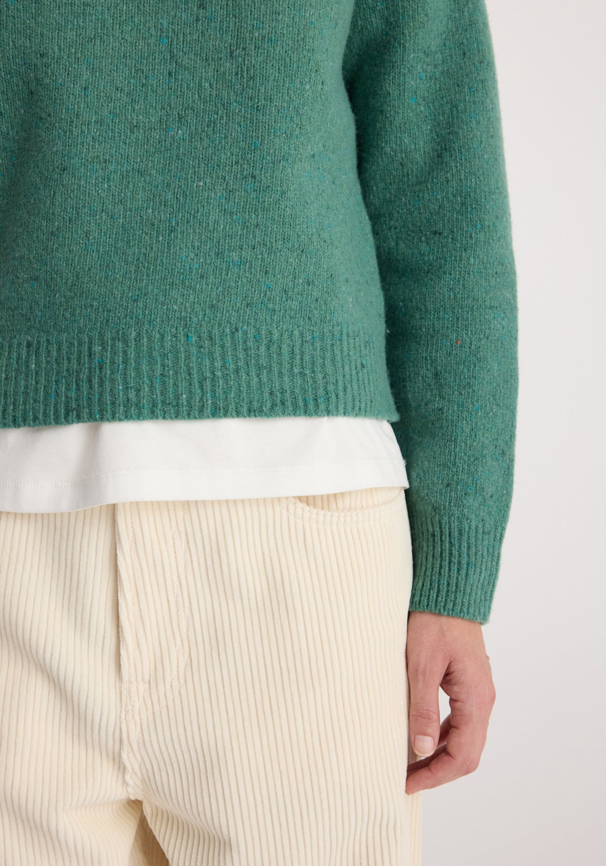 Fitted mouliné crewneck | jade mouliné in textured jade green knit, layered over a white shirt and paired with cream pleated trousers.