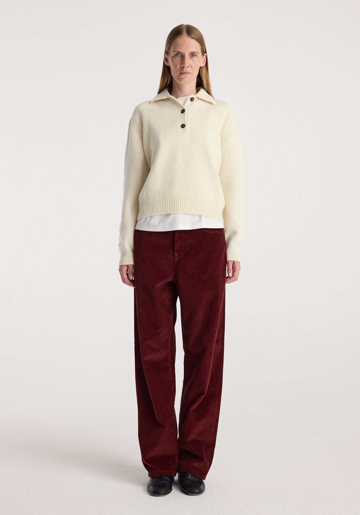 Woman wearing Bruun - Signature baggy corduroy trousers | wine paired with a cream long-sleeve sweater, standing against a plain white background.