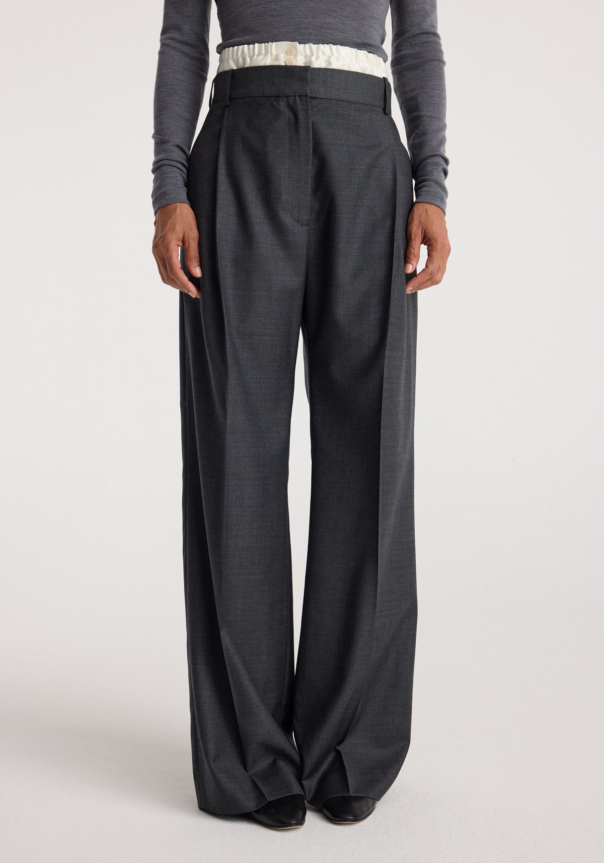 Front view of a person wearing Boxer detailed trousers | dark grey melange, featuring a high waist and wide-leg fit paired with a tucked-in long sleeve top.