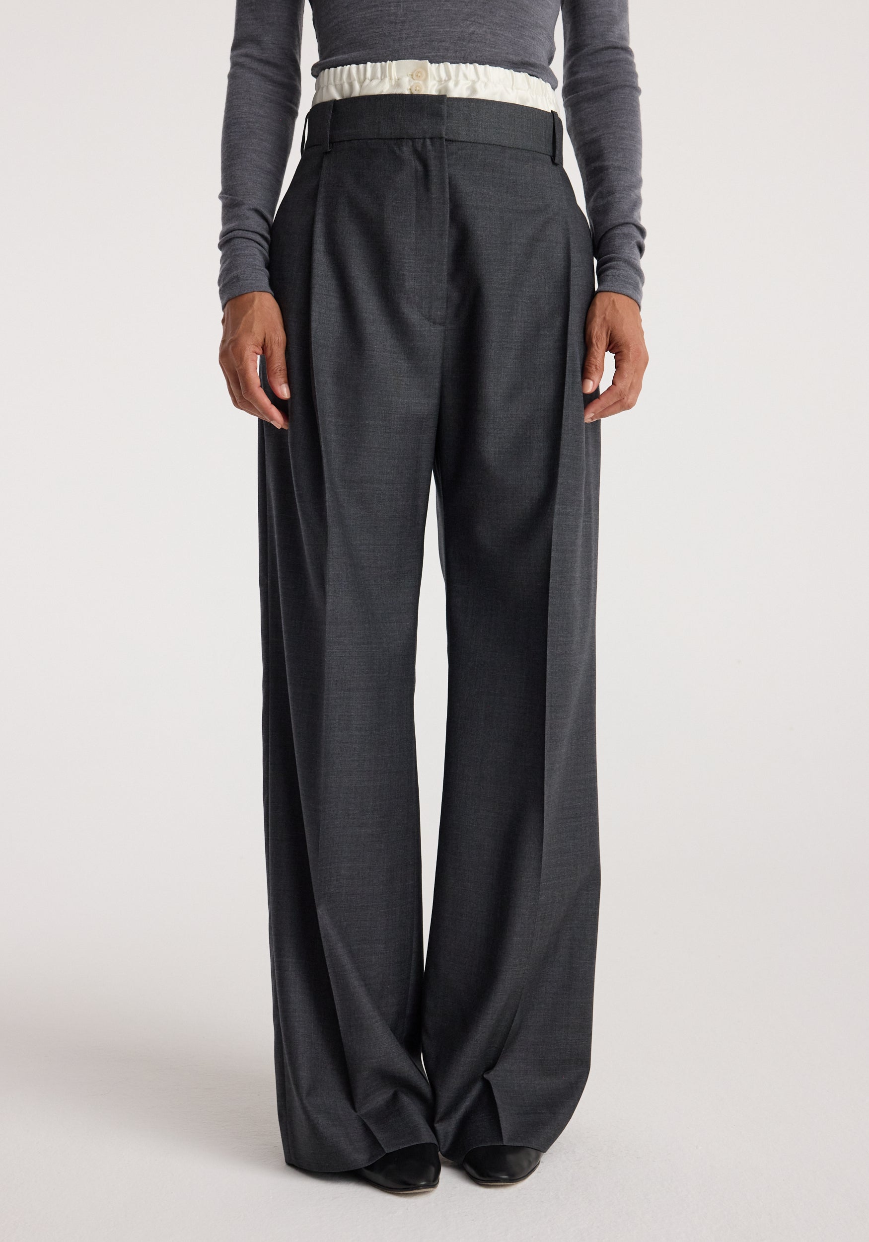Front view of a person wearing Boxer detailed trousers | dark grey melange, featuring a high waist and wide-leg fit paired with a tucked-in long sleeve top.