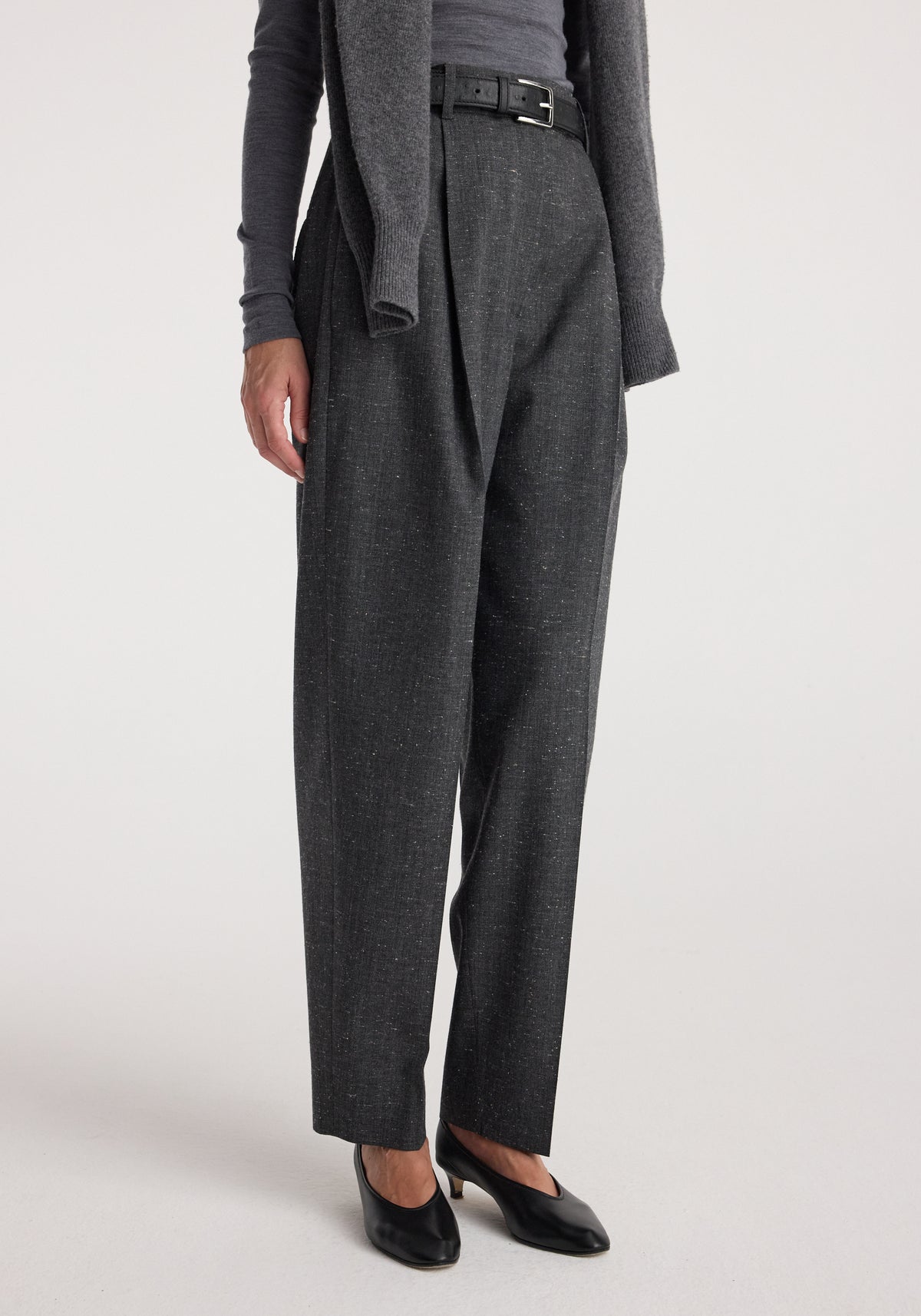 Close-up of a person wearing Daria - Single pleat straight leg trousers | grey slub paired with black heels and a grey top with a matching cardigan draped over the shoulders.