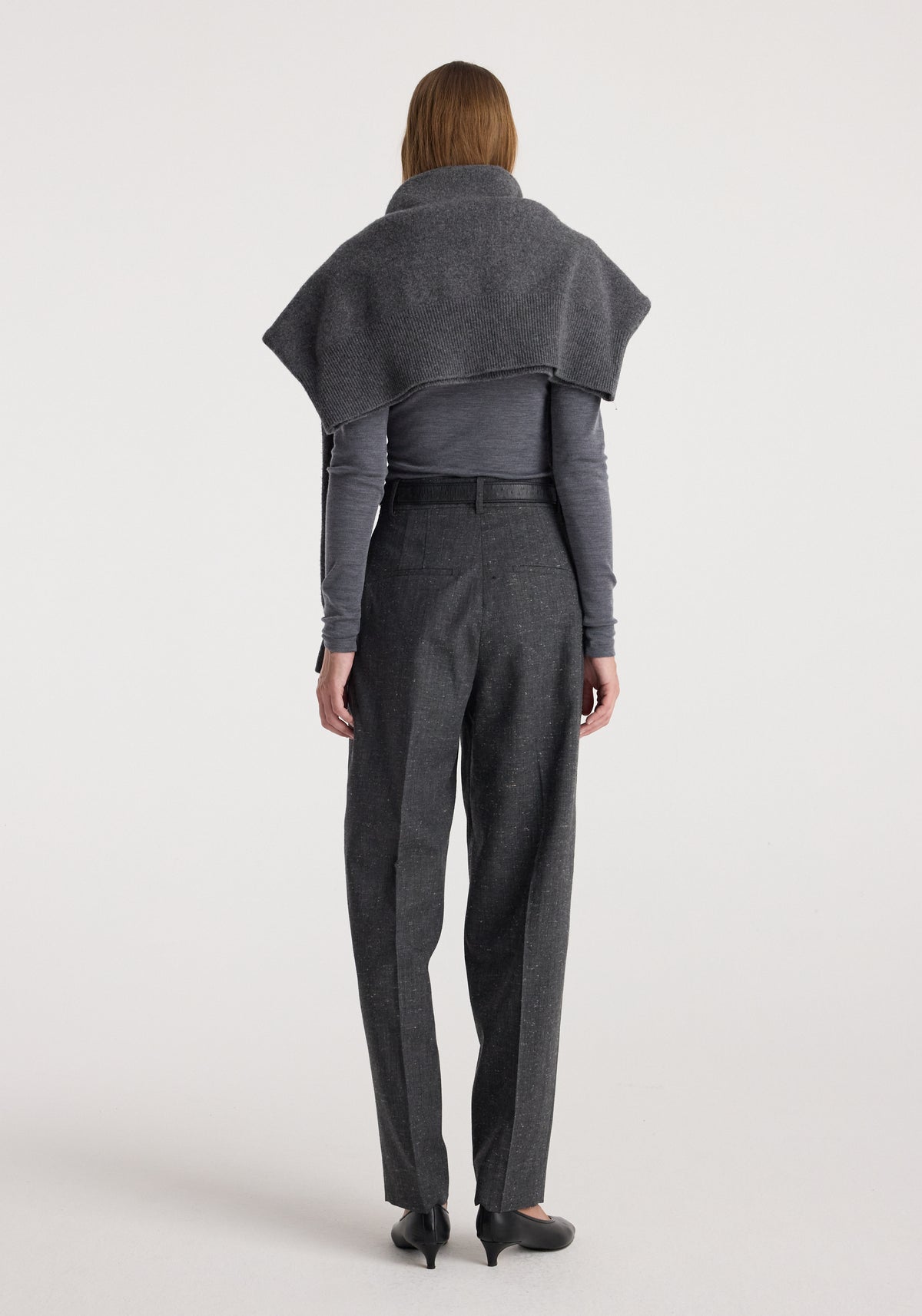 Woman wearing Daria - Single pleat straight leg trousers | grey slub, paired with a fitted long sleeve top and a draped shawl over her shoulders, photographed from the back.