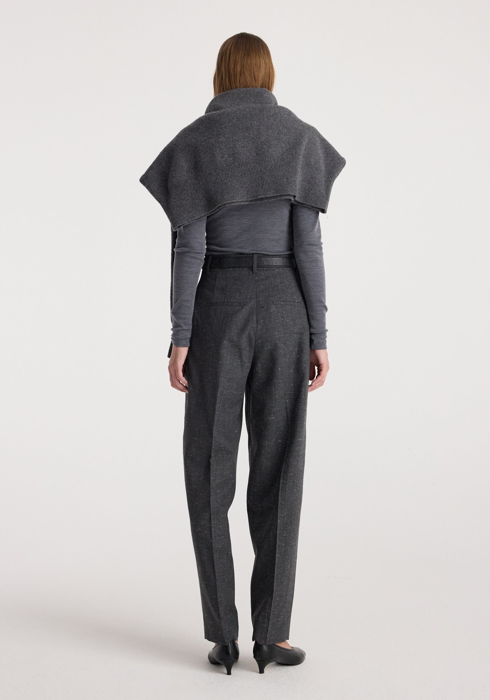 Woman wearing Daria - Single pleat straight leg trousers | grey slub, paired with a fitted long sleeve top and a draped shawl over her shoulders, photographed from the back.