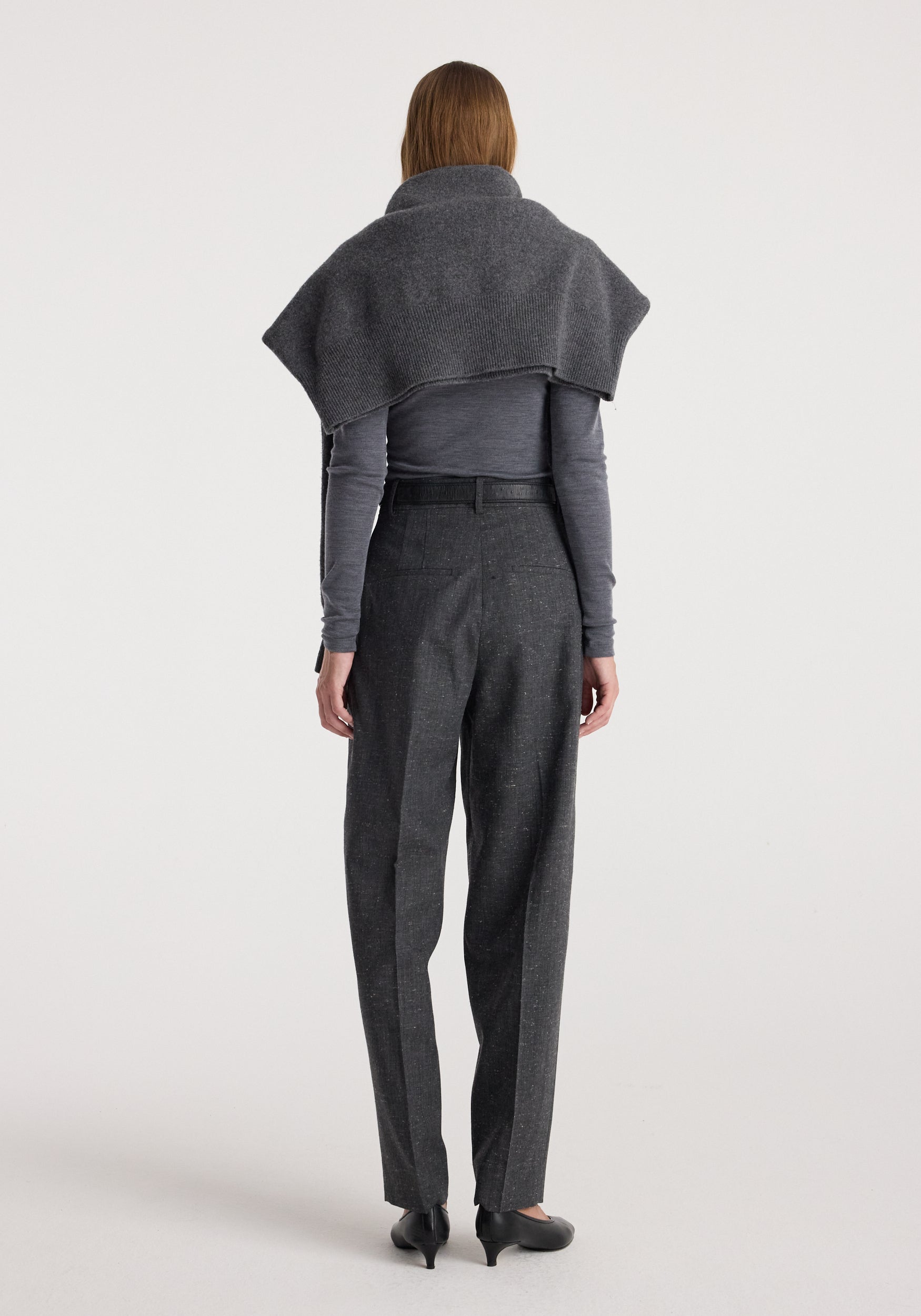 Woman wearing Daria - Single pleat straight leg trousers | grey slub, paired with a fitted long sleeve top and a draped shawl over her shoulders, photographed from the back.