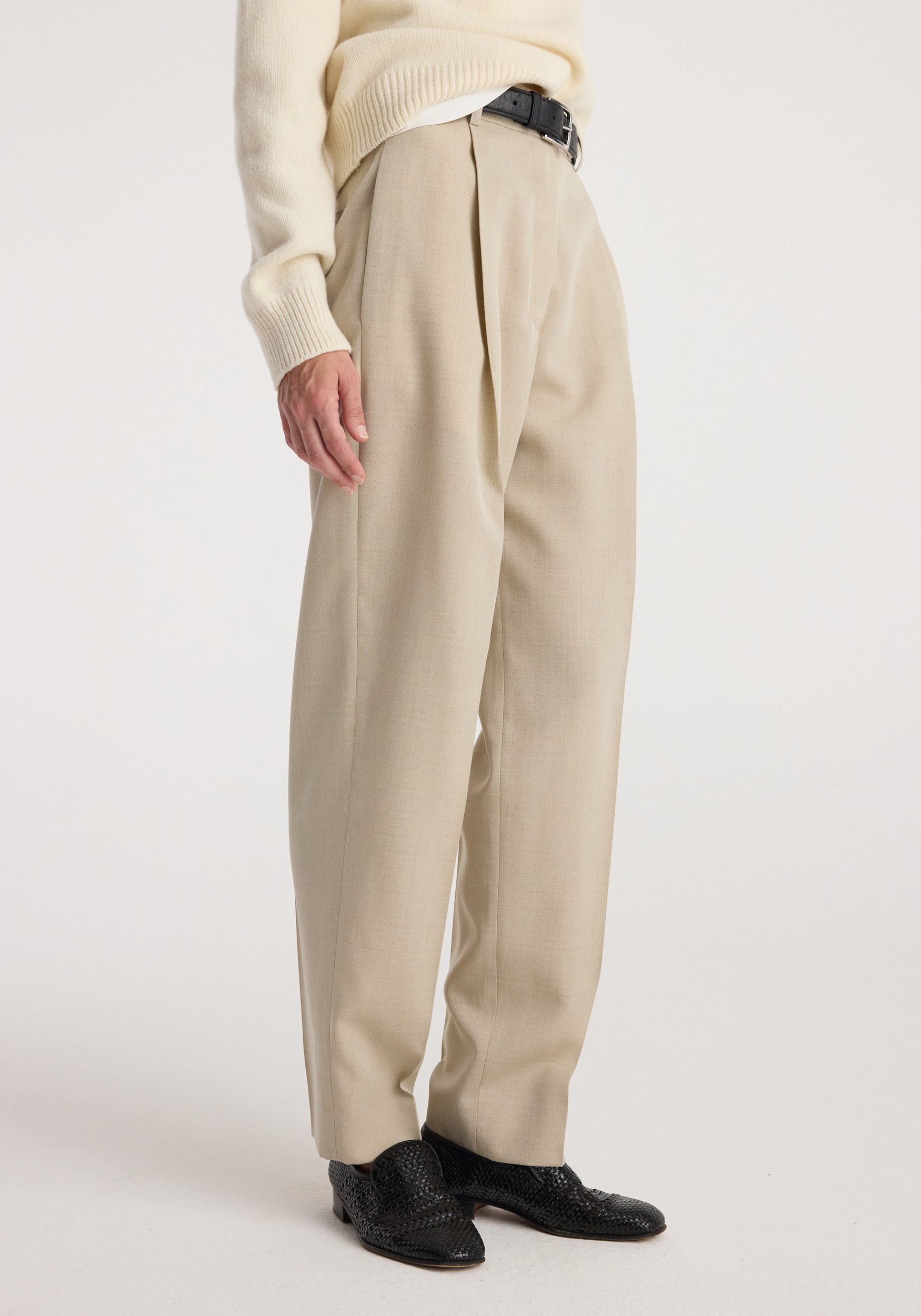 Close-up of a person wearing Daria - Single pleat straight leg trousers | butter with a cream sweater and black textured shoes, showcasing the tailored fit and pleated detail.
