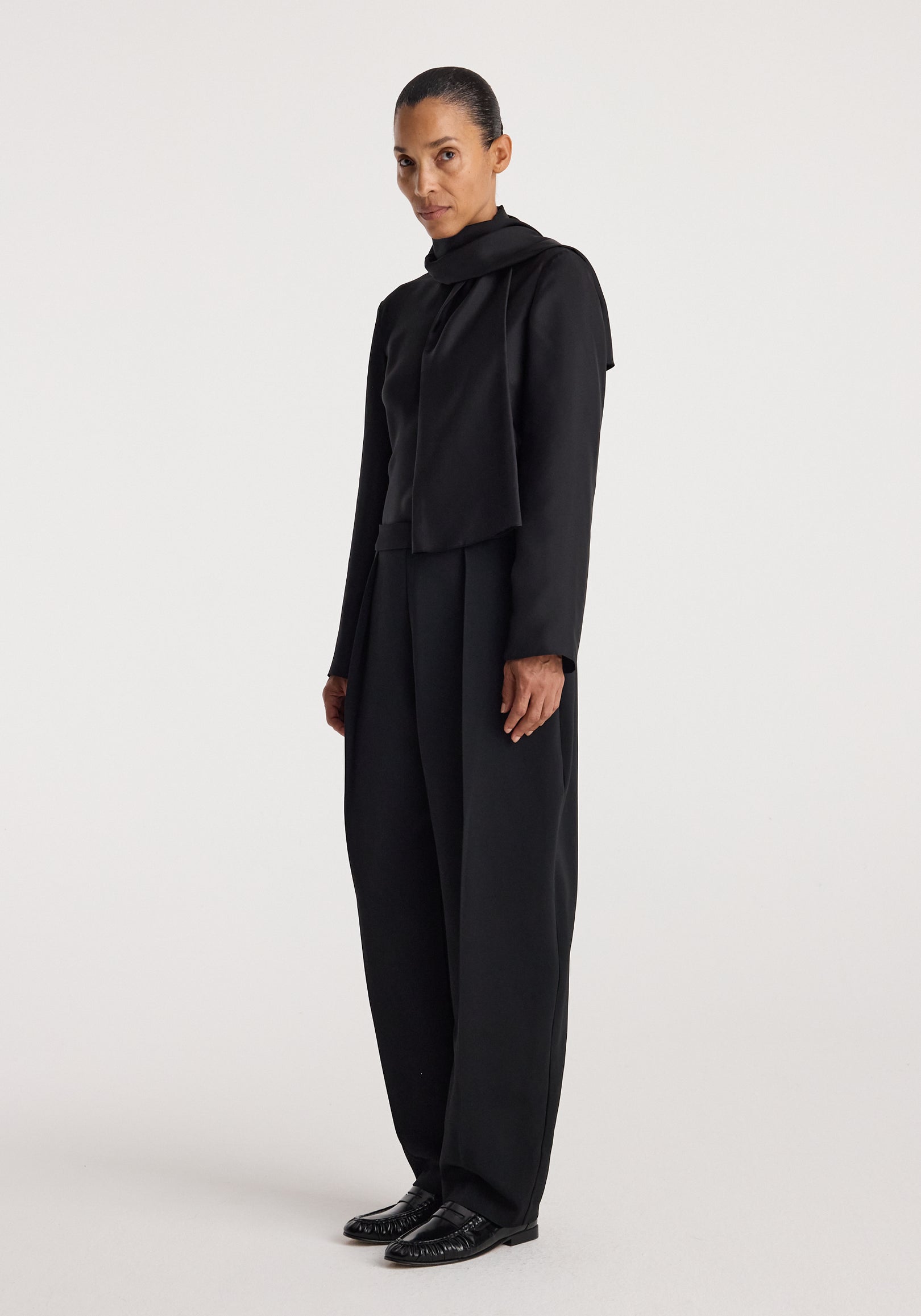 Puck - Sculptural tailored trousers | black worn by a model in a full-length studio portrait, styled with a black top and polished black shoes
