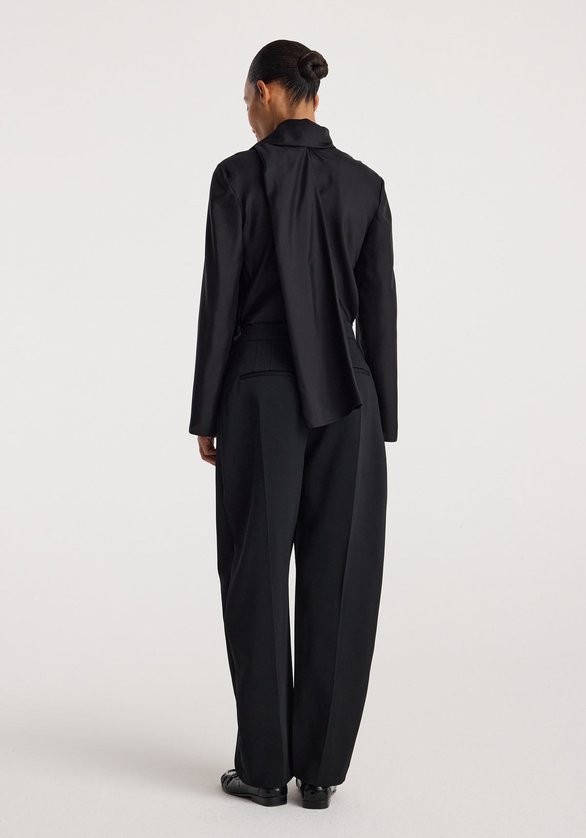 Back view of a model wearing black sculptural tailored trousers with a relaxed wide-leg silhouette. Puck - Sculptural tailored trousers | black