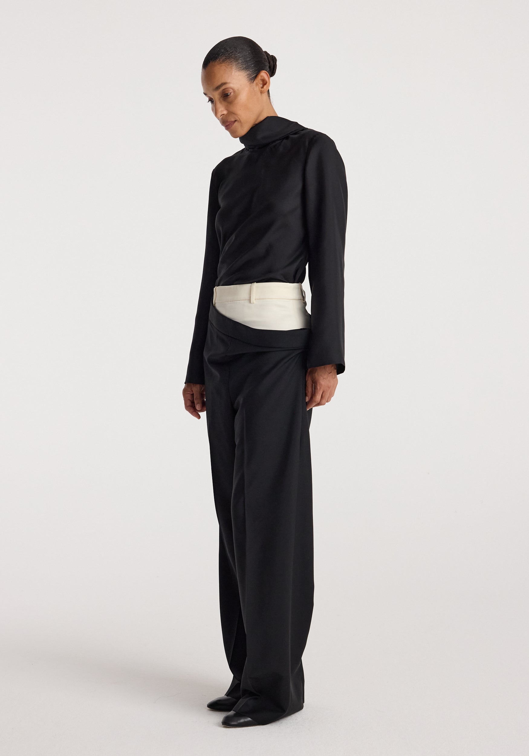 Model wearing black Double waistband trousers | black with a contrasting white double waistband detail, paired with a black long-sleeve top and black shoes, standing against a plain white background.
