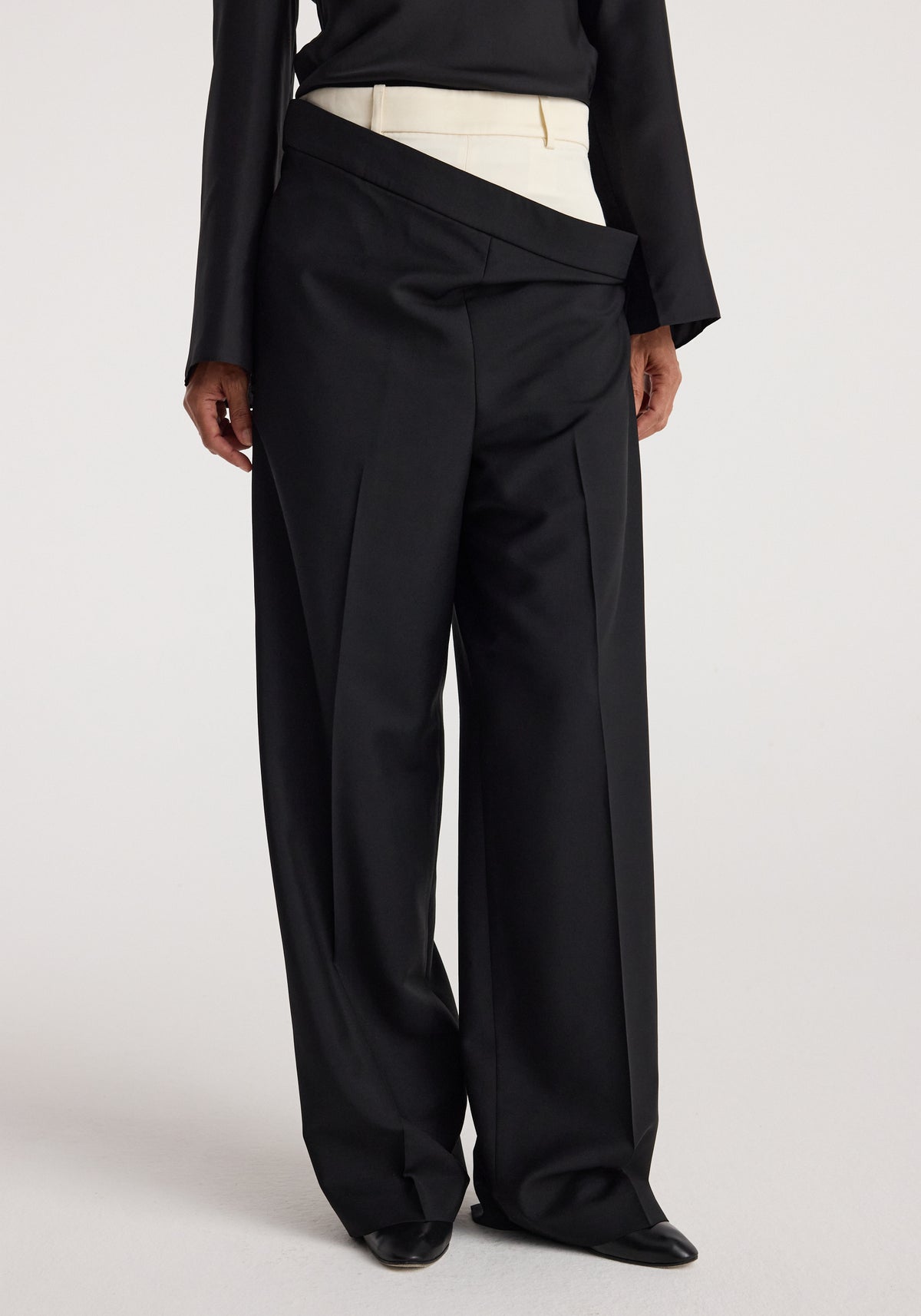 Black wide-leg Double waistband trousers | black styled on a person wearing a black top and cream inner waistband visible beneath the overlapping double waistband design.