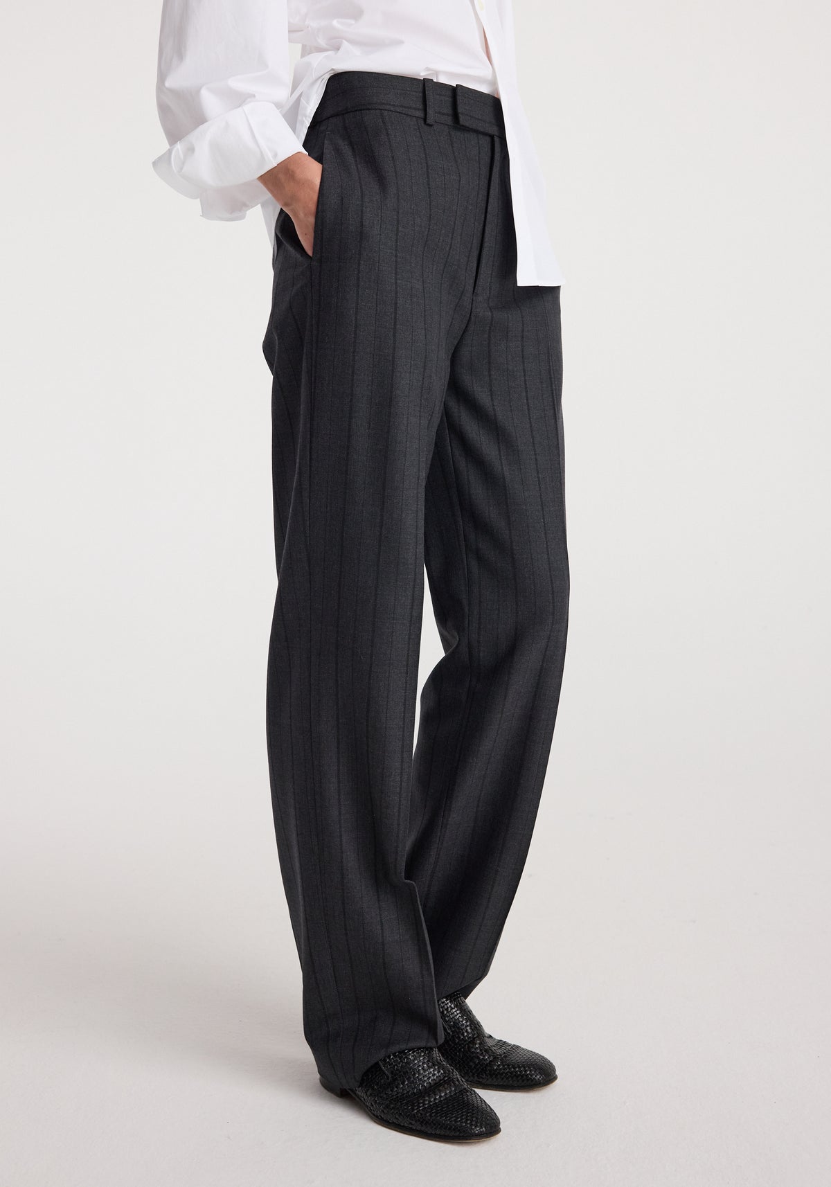 Side view of a person wearing Kee - Straight leg tailored trousers | charcoal stripe, paired with black textured shoes and a white shirt with sleeves rolled up.