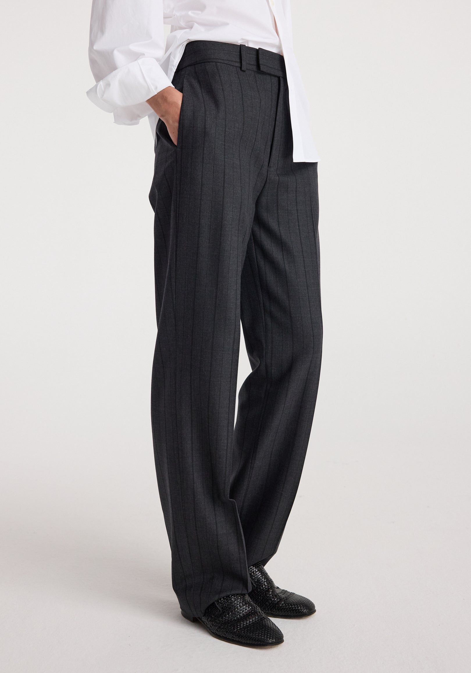 Side view of a person wearing Kee - Straight leg tailored trousers | charcoal stripe, paired with black textured shoes and a white shirt with sleeves rolled up.