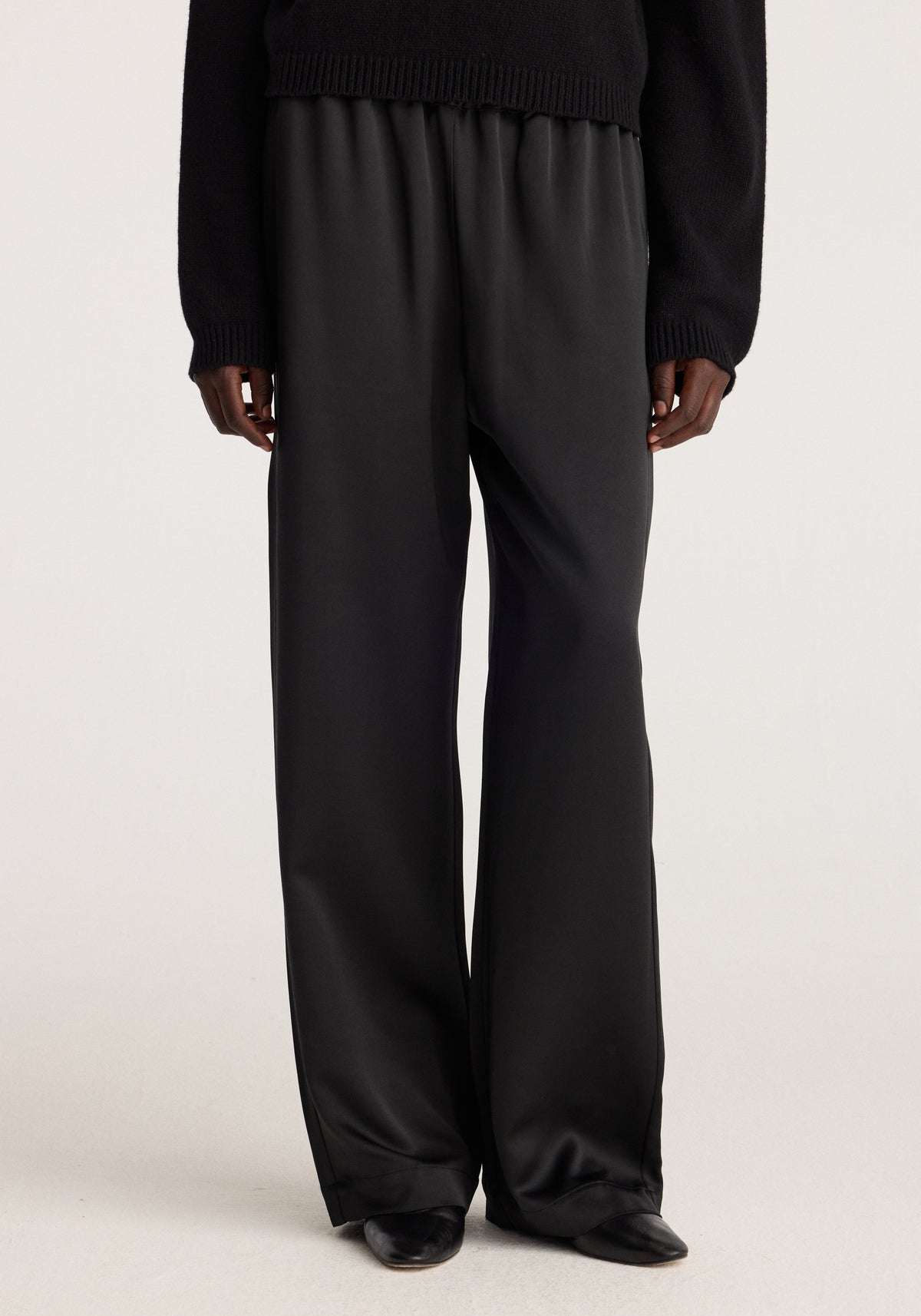 Relaxed fit satin trousers | black shown on a model with a fluid satin finish elasticated waist wide legs and full length styling