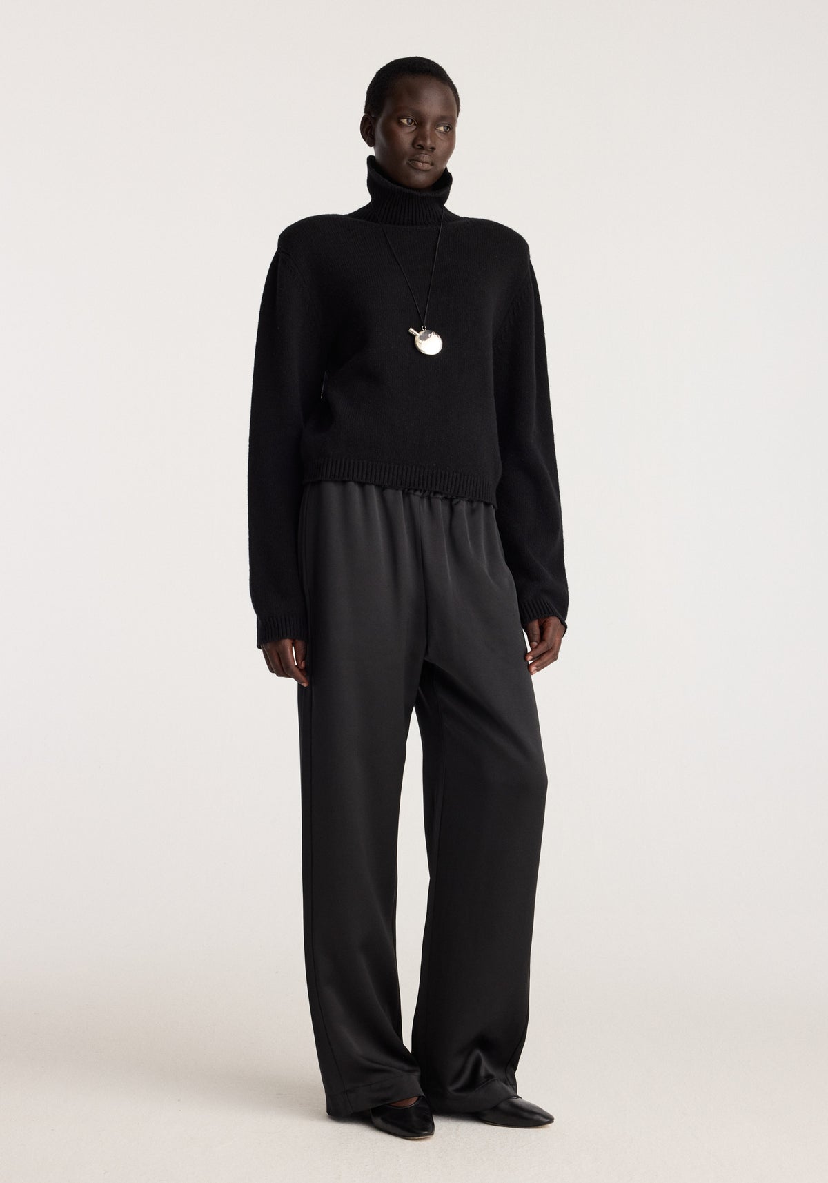 Relaxed fit satin trousers | black shown on a model with a relaxed leg, elasticated waist and flowing satin finish in a minimalist studio setting