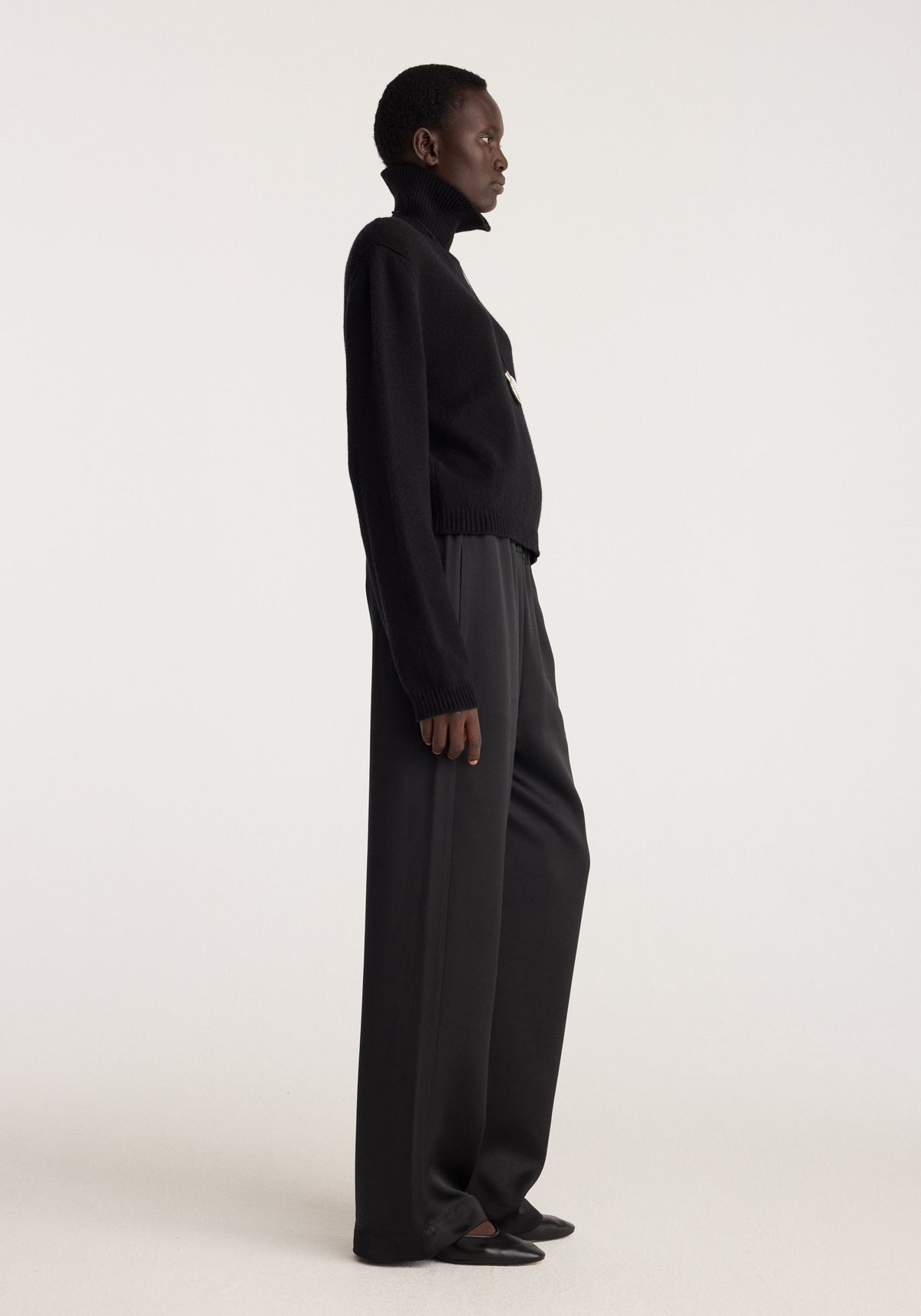 Relaxed fit satin trousers | black shown on a model in side profile with a flowing wide leg silhouette and subtle satin sheen