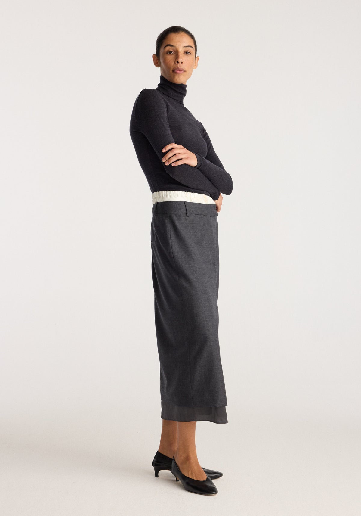 Boxer detailed skirt | dark grey melange worn by a model with a straight below knee silhouette and subtle textured fabric styled with a black turtleneck.