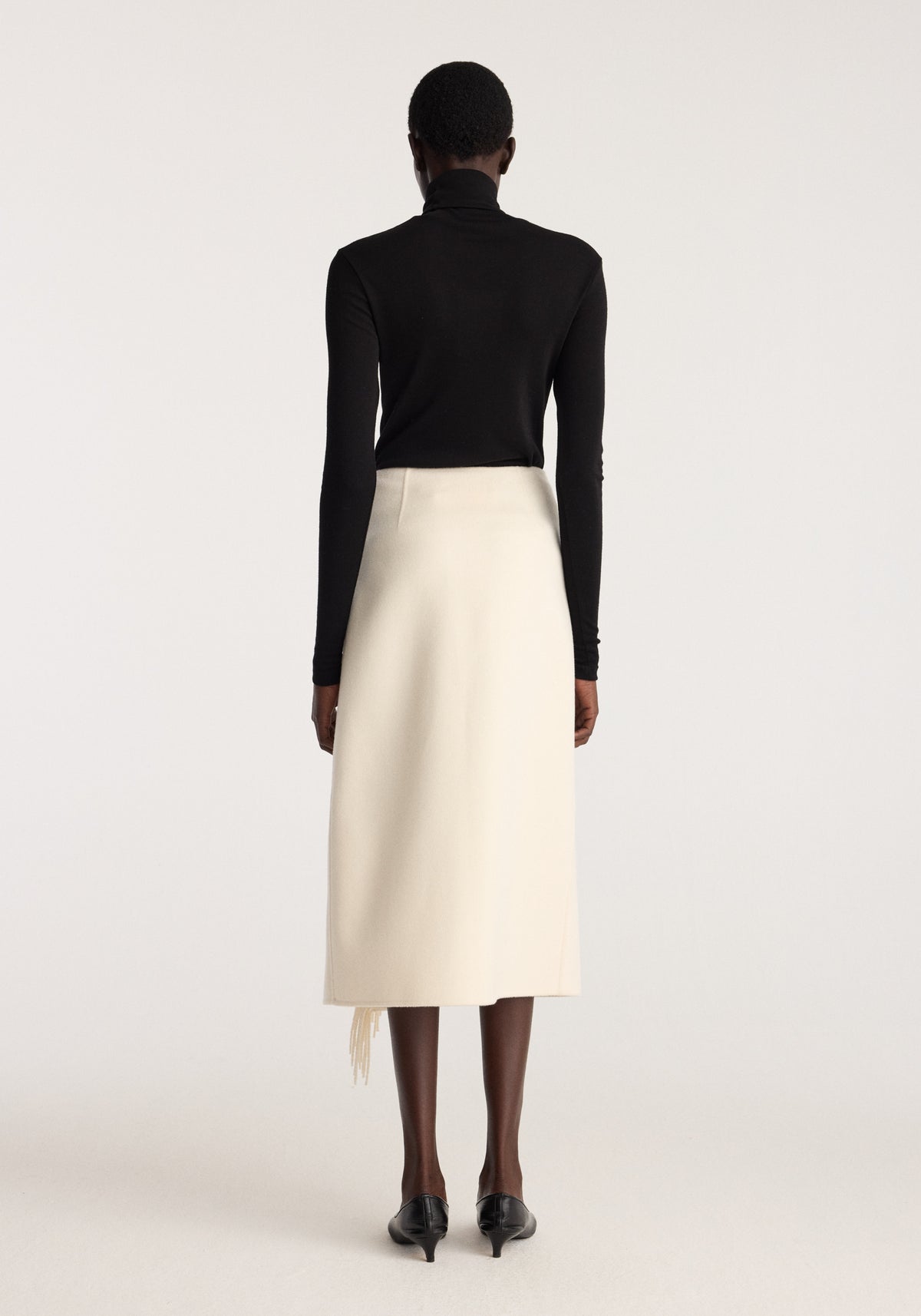 Double-faced fringe skirt | off white shown from the back on a model with a black long sleeve top and black heels
