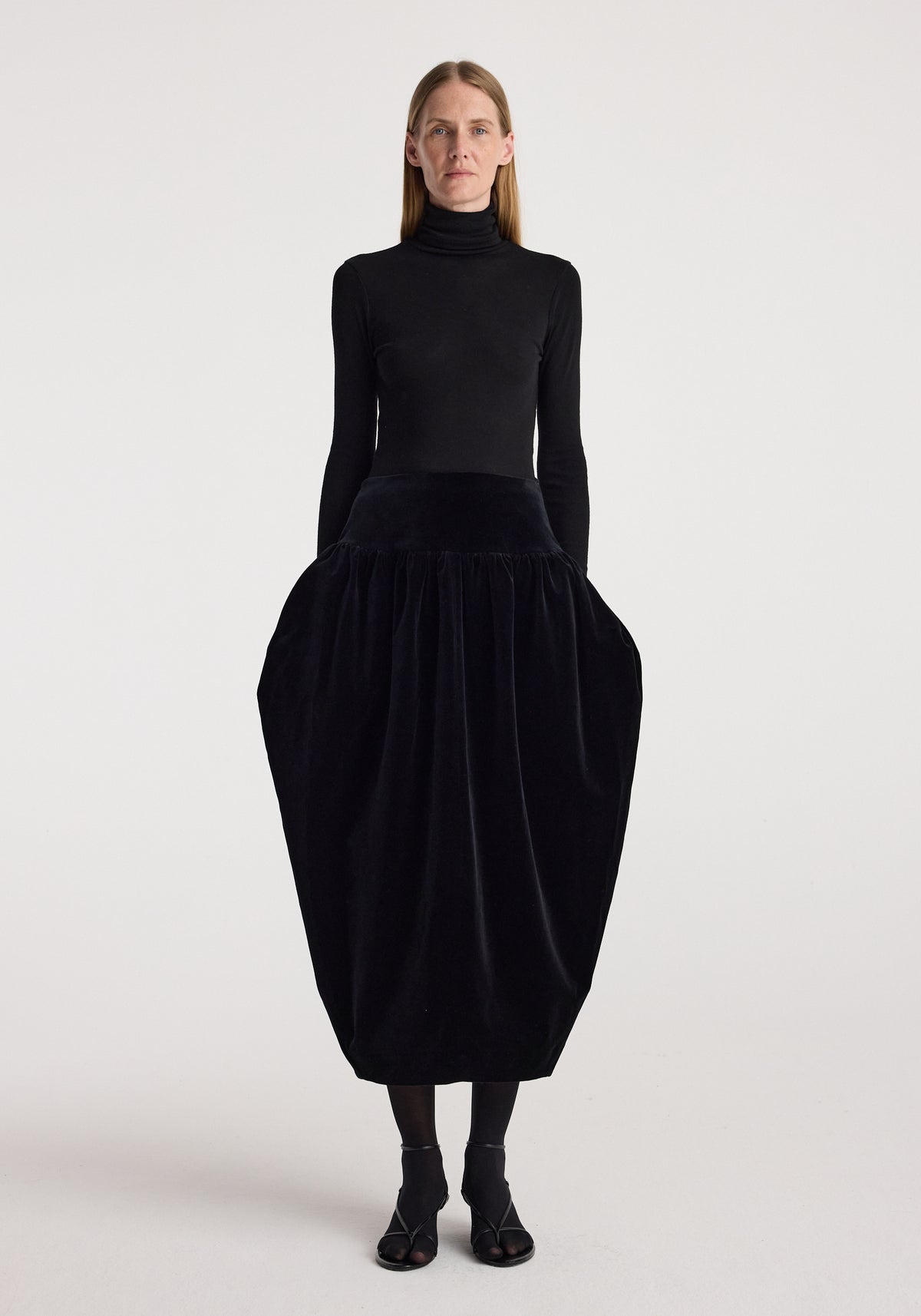 Sculptural volume velvet skirt | black worn with a fitted black turtleneck and black sandals, featuring a dramatic rounded silhouette and gathered waist