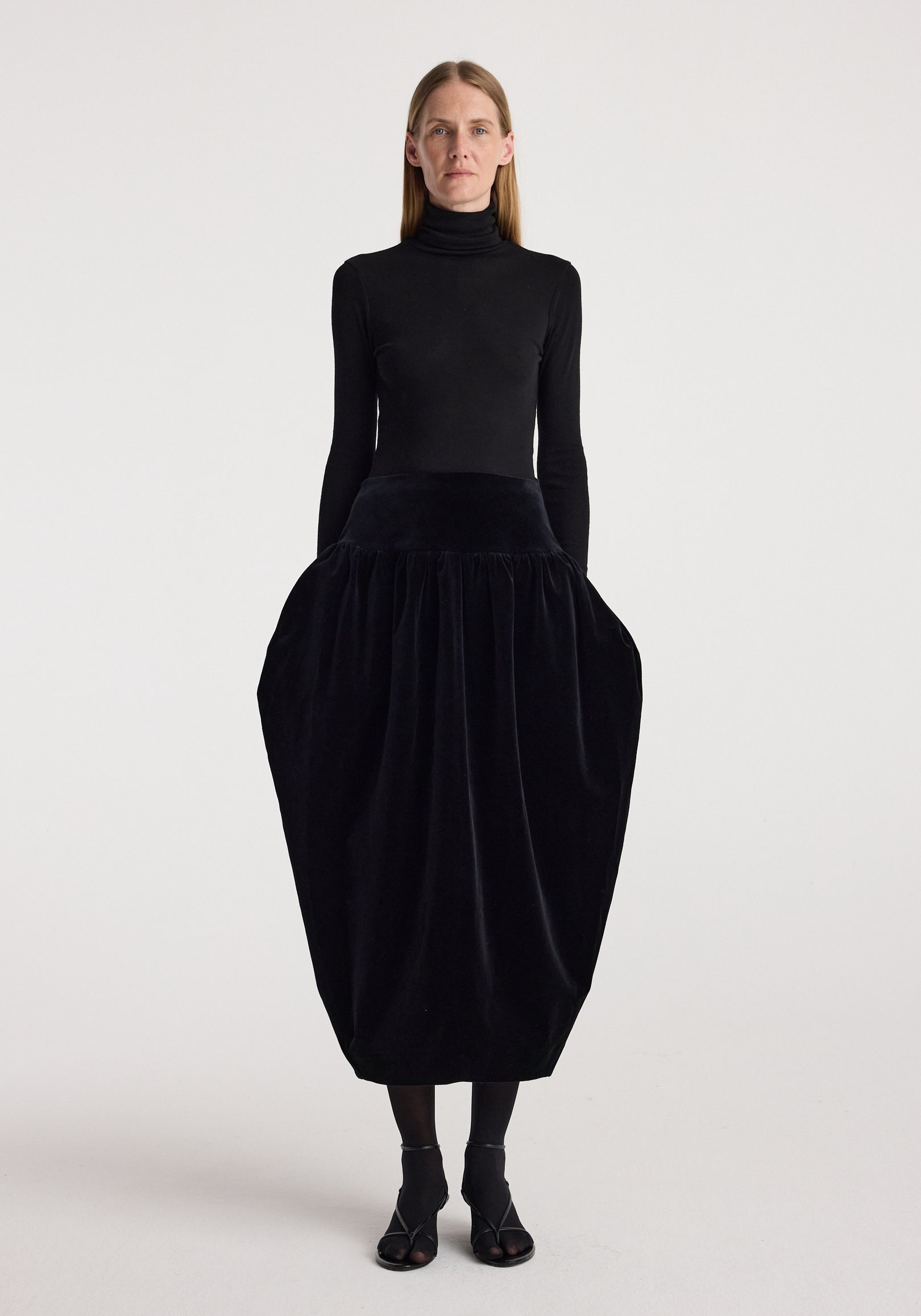 Sculptural volume velvet skirt | black worn with a fitted black turtleneck and black sandals, featuring a dramatic rounded silhouette and gathered waist