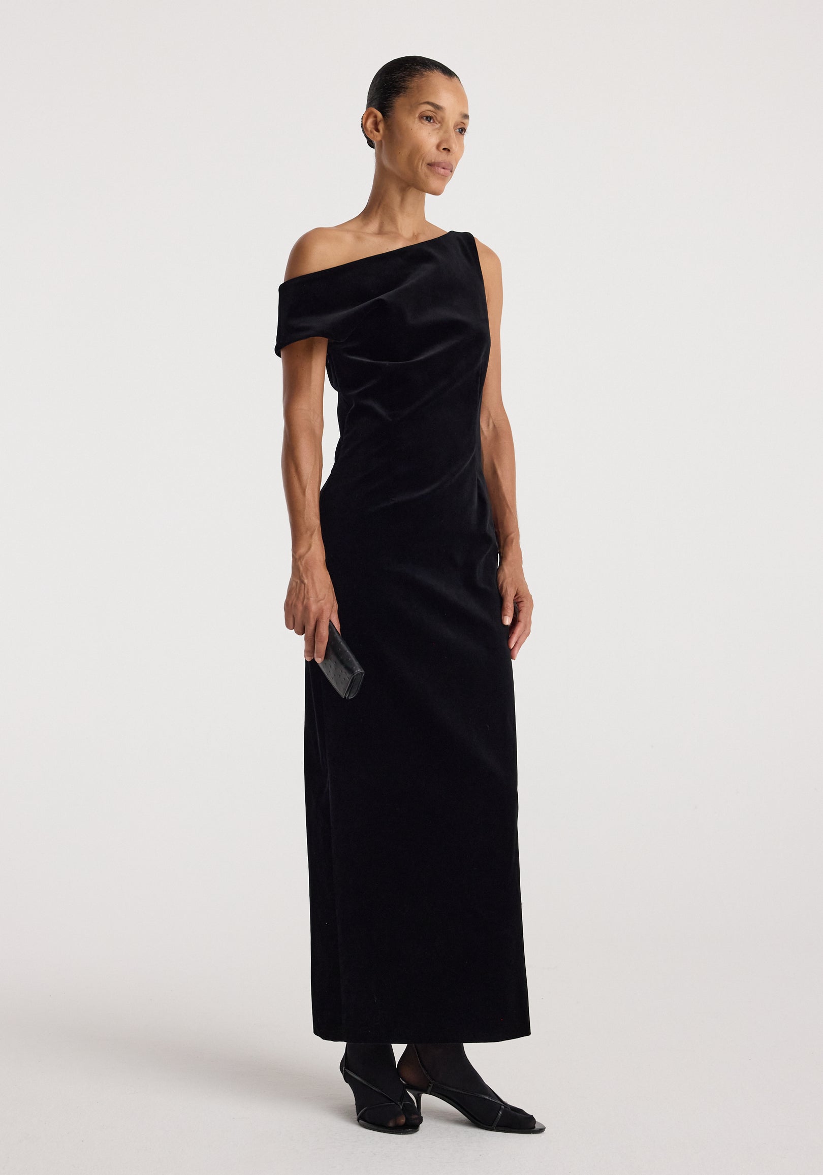 Sculptural off-shoulder velvet gown | black, modeled in a sleek floor-length silhouette with an asymmetrical neckline and draped shoulder detail