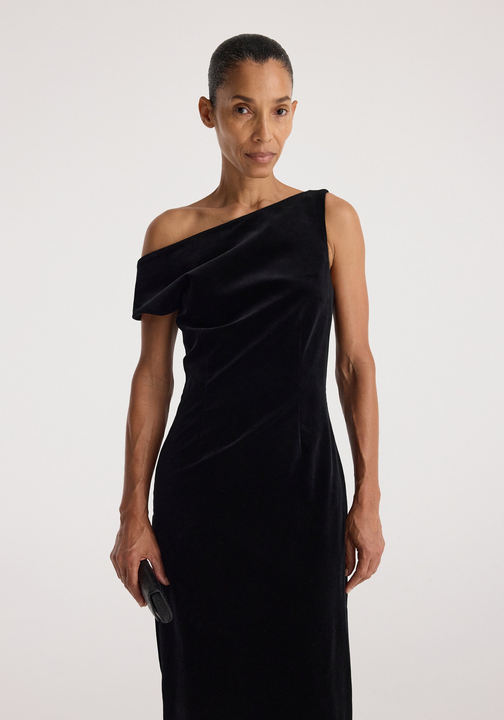 Sculptural off-shoulder velvet gown | black modeled in a sleek asymmetrical silhouette with a draped neckline and fitted shape