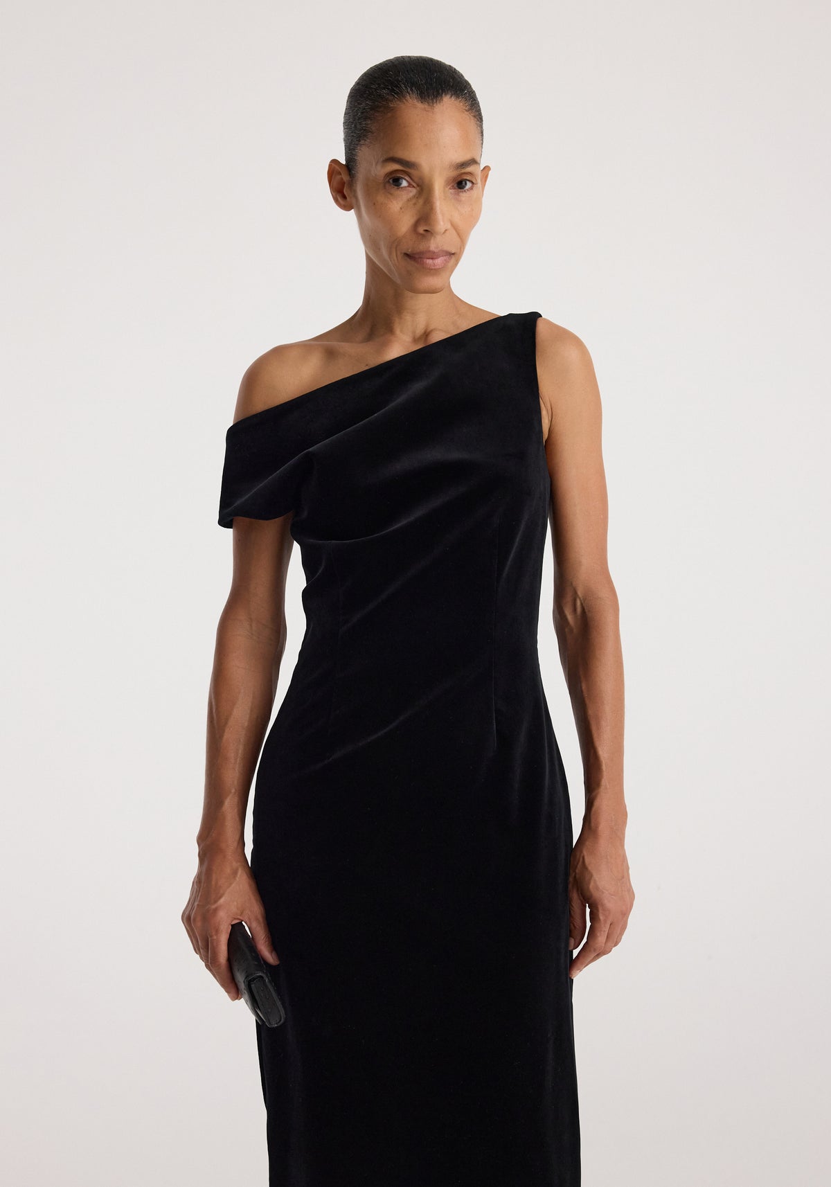 Sculptural off-shoulder velvet gown | black modeled in a sleek asymmetrical silhouette with a draped neckline and fitted shape