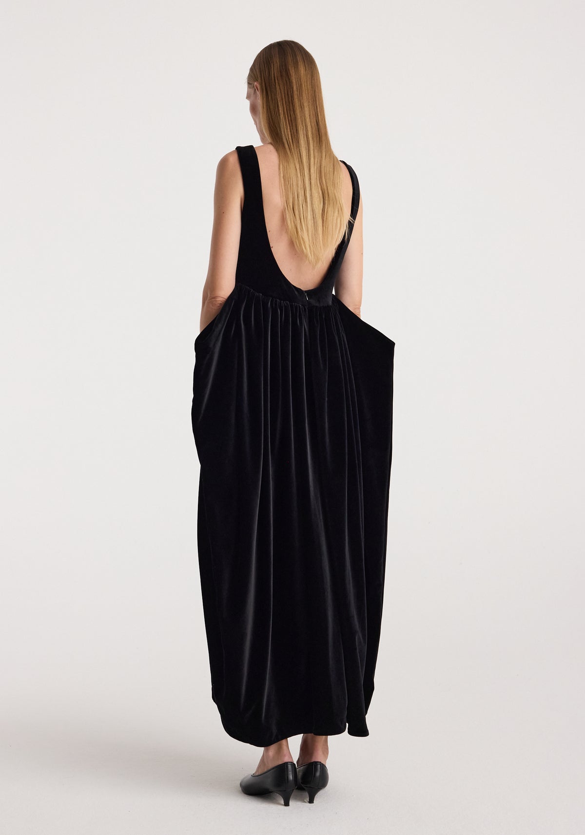 Sculptural volume velvet dress | black shown from the back on a model, featuring a deep scoop back, gathered waist, and flowing full length silhouette