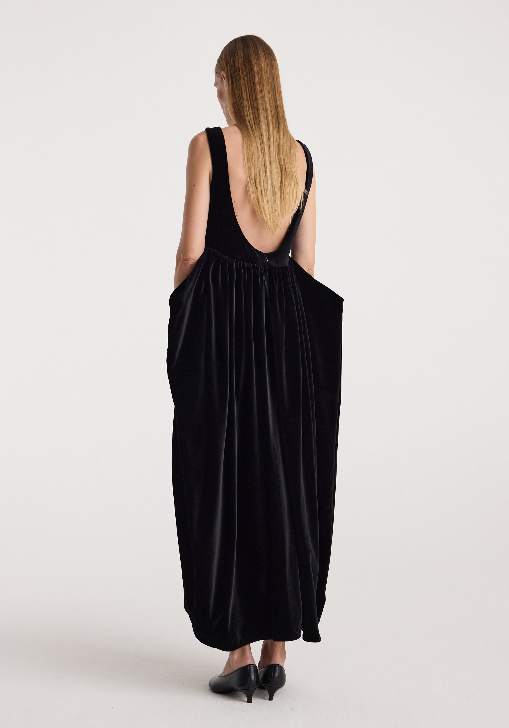 Sculptural volume velvet dress | black shown from the back on a model, featuring a deep scoop back, gathered waist, and flowing full length silhouette