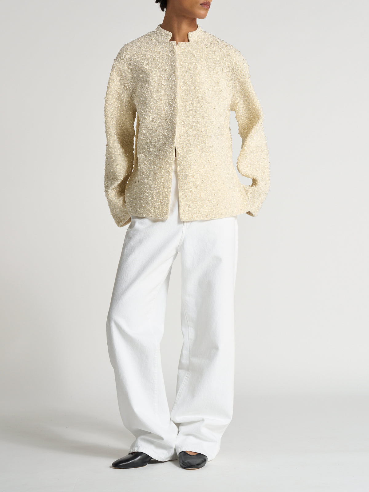Hand-beaded pearl pankou jacket | pearl worn with white trousers and black shoes in a minimalist studio setting, showcasing its cream textured finish and relaxed fit