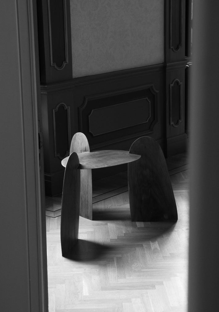 Sculpted Stool | 4673, a handcrafted oak stool by Arne Kristian, features interlocking slab legs and a triangular top, showcasing biophilic design on a parquet floor.