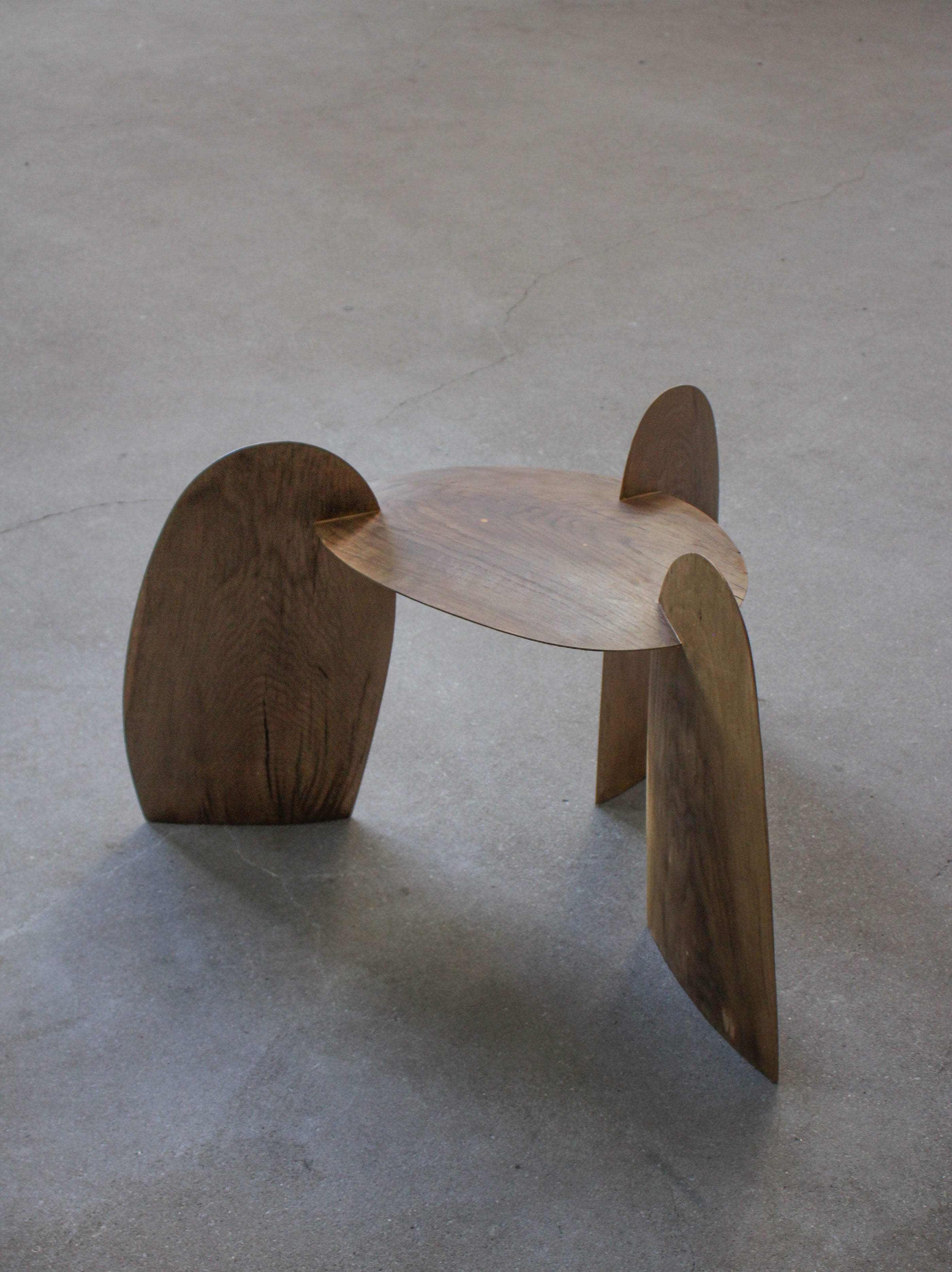 Sculpted Stool | 4673: A low, sculptural stool crafted from interlocking oak panels, forming tripod legs and a round, dished top. Handcrafted by Arne Kristian.