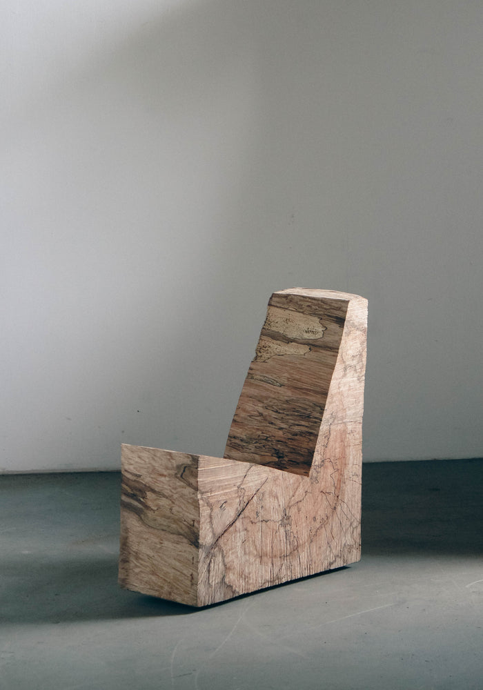 Brutalist Chair | 5788: A raw, L-shaped oak wood block, showcasing rough chainsaw cuts, exemplifying minimalist design by Arne Kristian, blending sculpture with functionality.