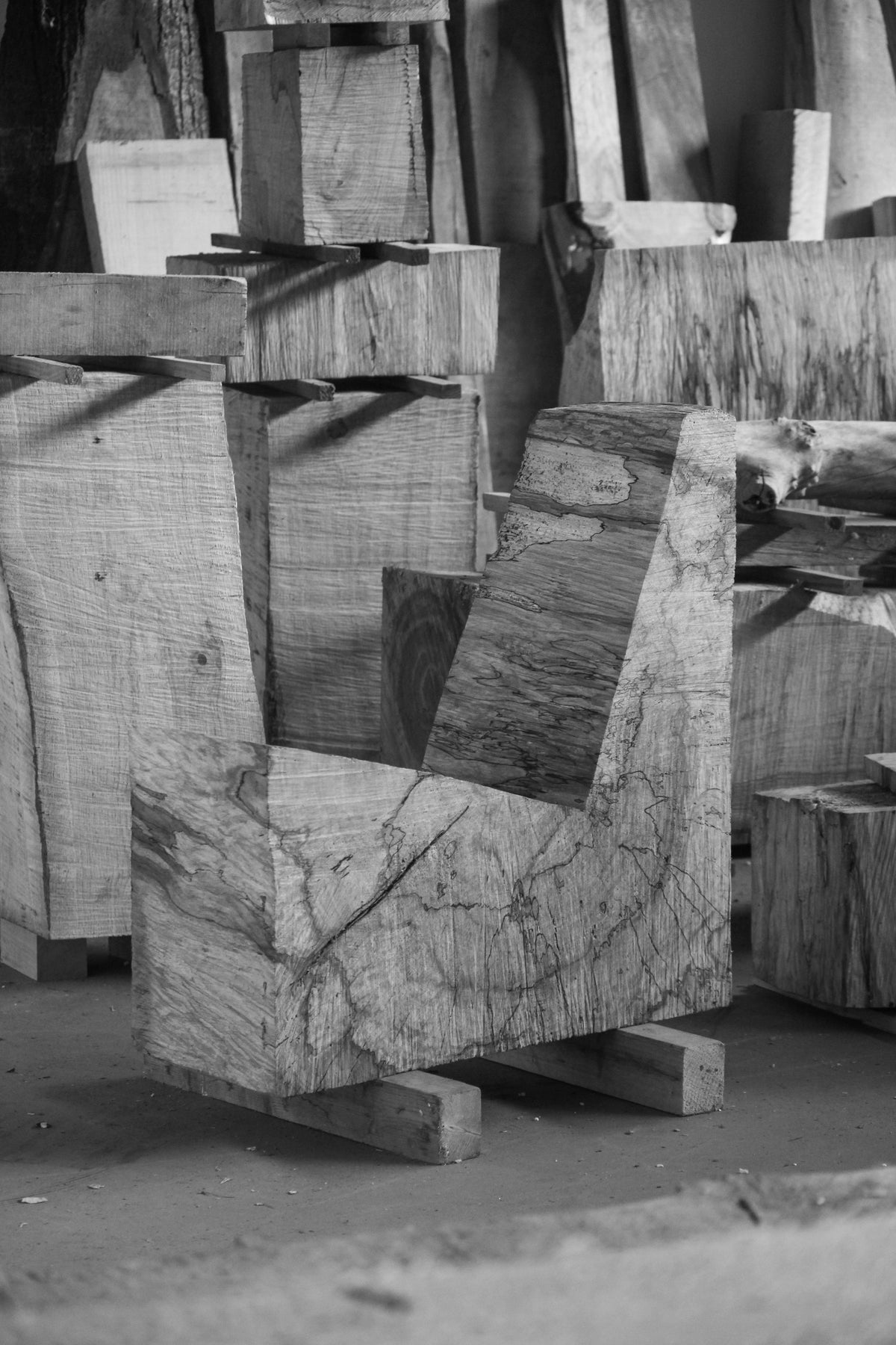 Brutalist Chair | 5788: L-shaped oak block with visible grain and spalting, showcasing rough chainsaw cuts, emphasizing the raw beauty and functionality in a workshop setting.