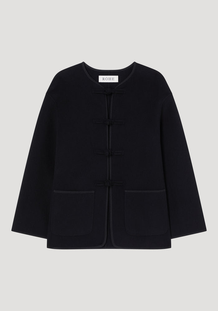 Double-faced wool pankou jacket with round neckline, long sleeves, embroidered edges, patch pockets, and frog closures, showcasing artisanal craftsmanship in a sleek silhouette.