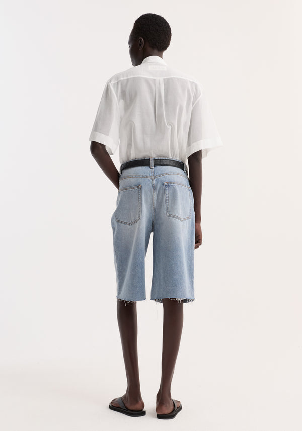 Back view of a model wearing the Embroidered muslin shirt in optic white, featuring drop short sleeves, covered buttons, and delicate collar embroidery.