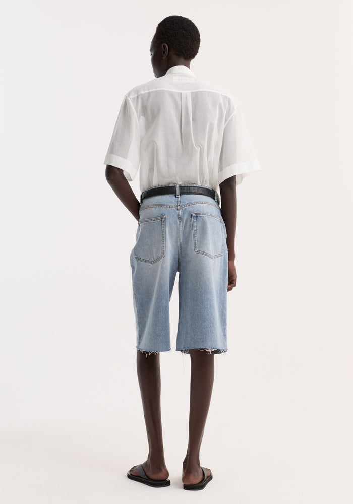 Back view of a model wearing the Embroidered muslin shirt in optic white, featuring drop short sleeves, covered buttons, and delicate collar embroidery.