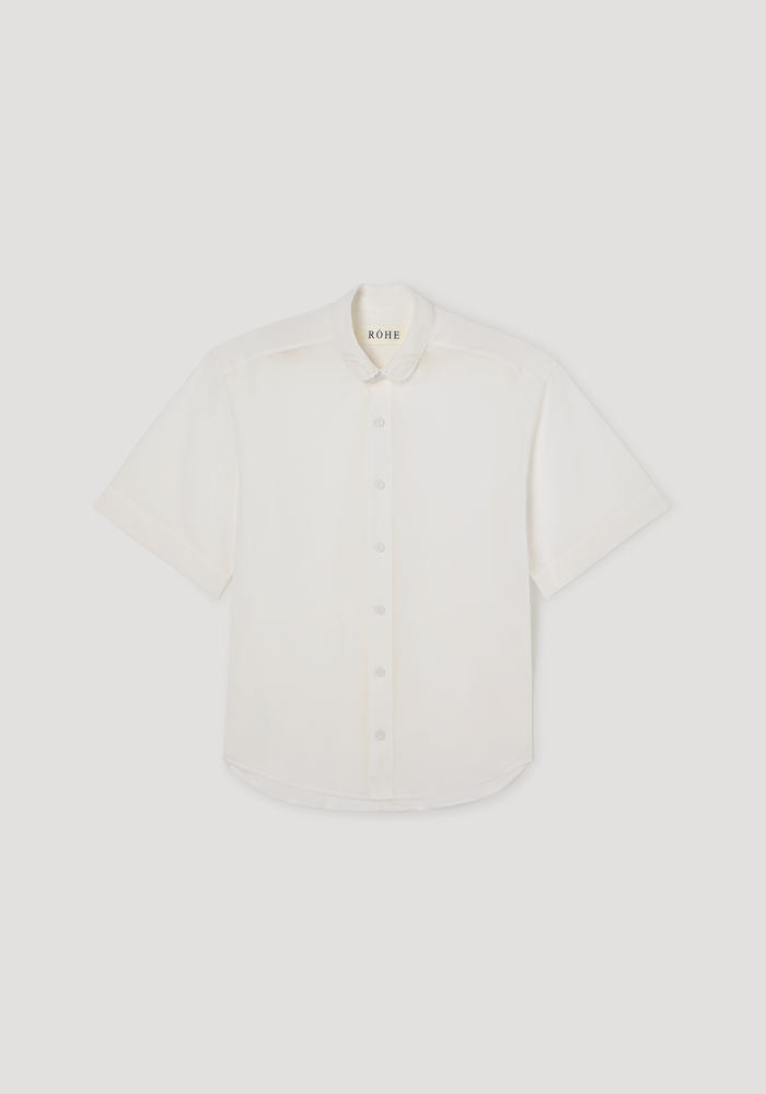 Embroidered muslin shirt in optic white, featuring sheer cotton fabric, short sleeves, covered buttons, and delicate embroidery on the scalloped collar.