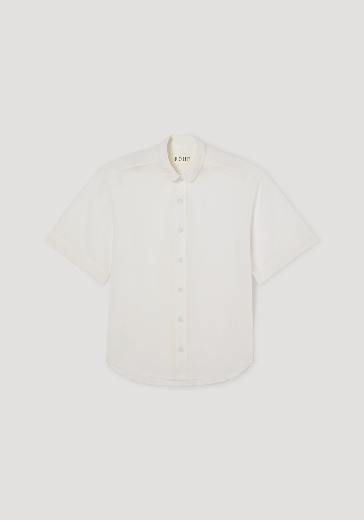 Embroidered muslin shirt in optic white, featuring sheer cotton fabric, short sleeves, covered buttons, and delicate embroidery on the scalloped collar.